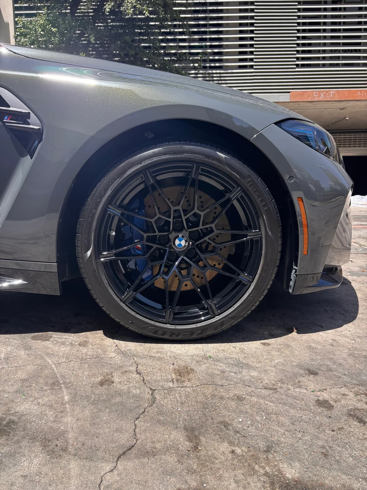 Close-up of a BMW M4 forged wheel, gold brake caliper and front fender.