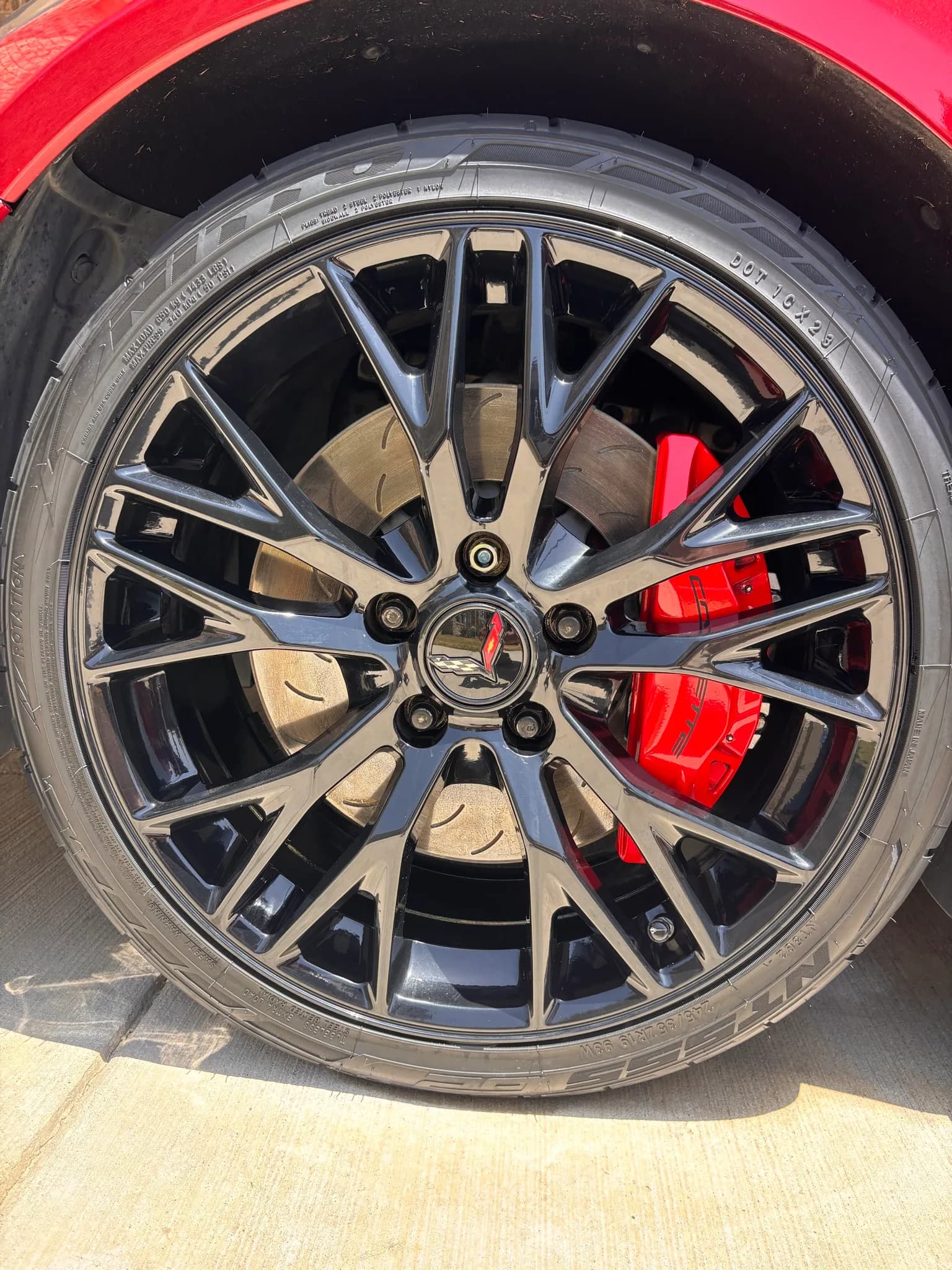 Straight-on view of a cleaned Corvette alloy wheel and dressed tire.