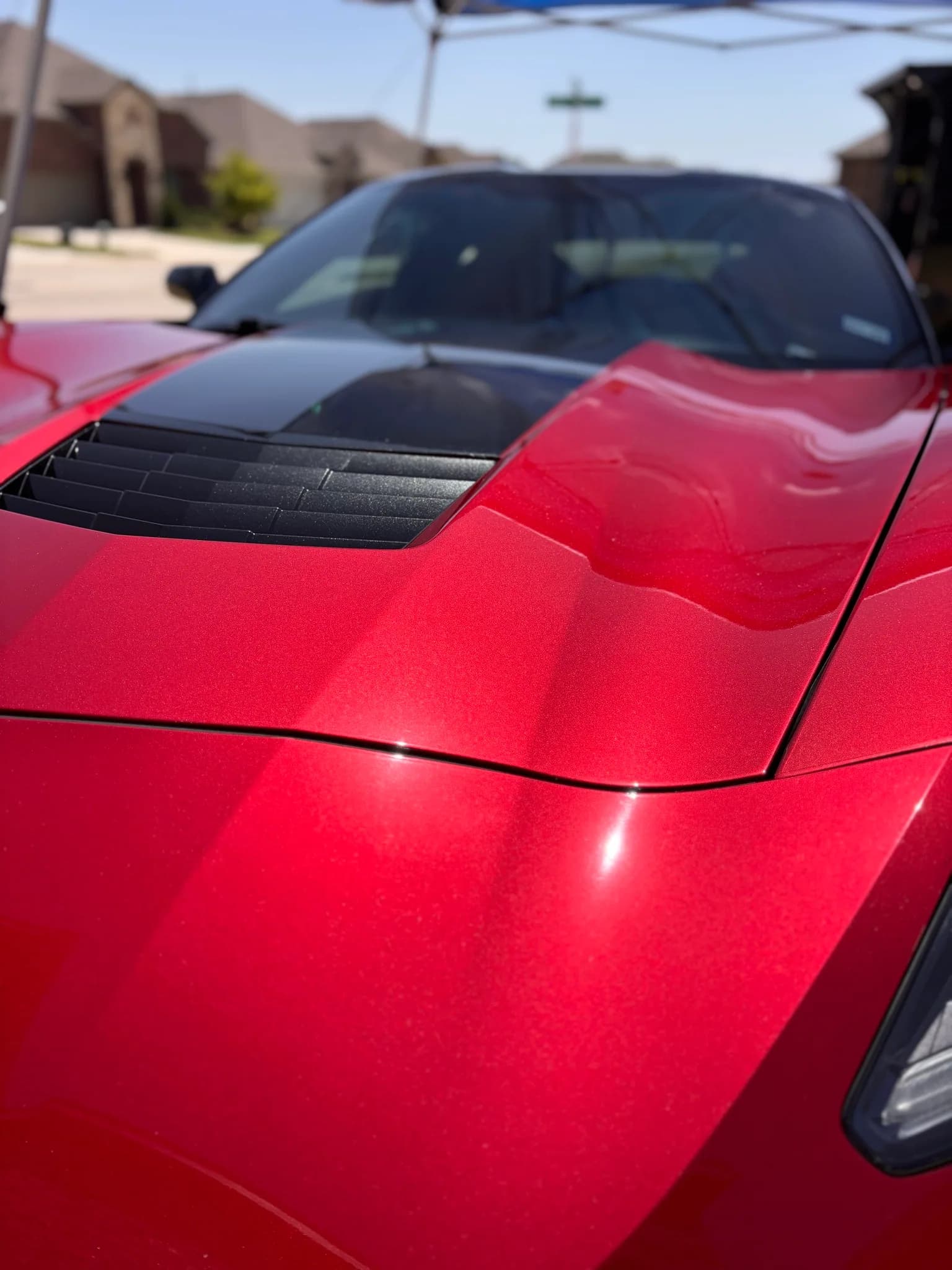 Glossy red hood and windshield cowl of a Corvette after paint decontamination.