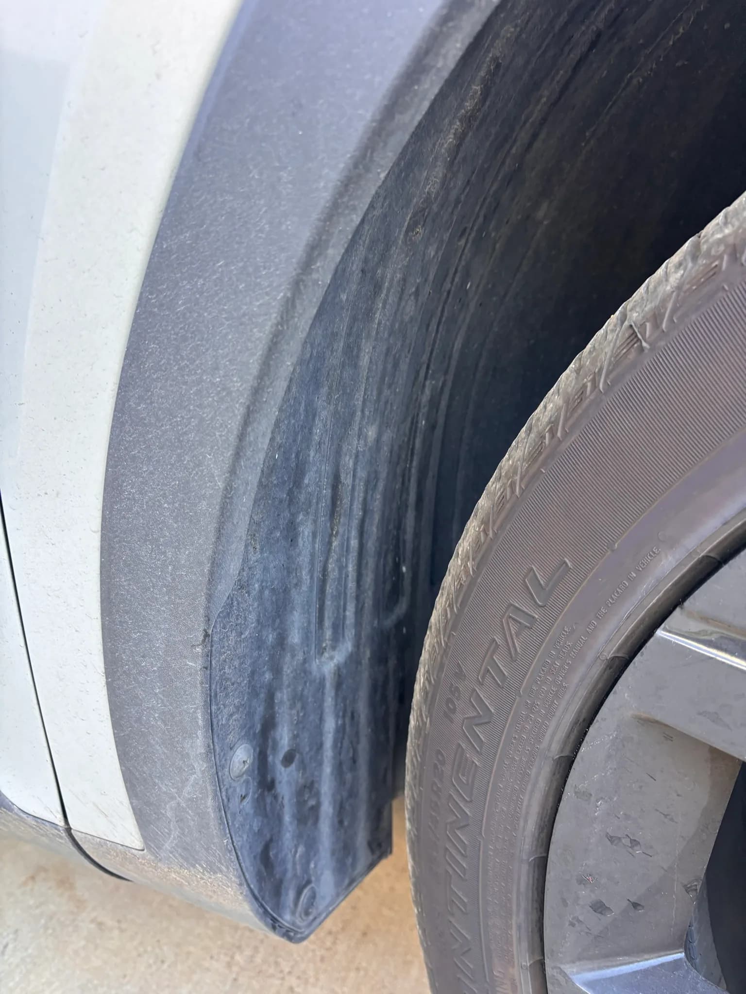 Close-up of a grimy wheel arch and tire sidewall on a white Kia Sorento.