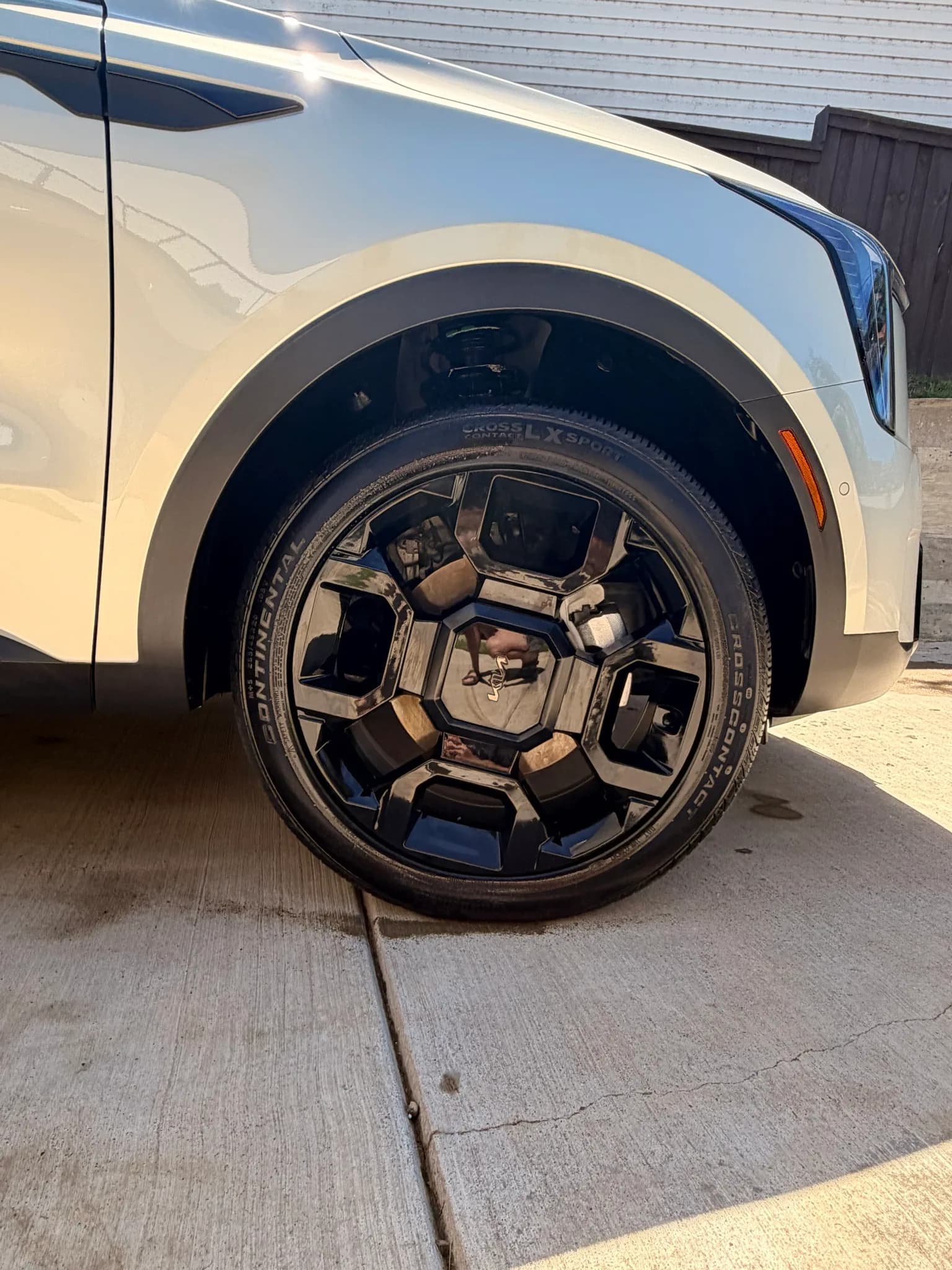 Close-up of a cleaned gloss black Kia alloy wheel and dressed Continental tire on a white Sorento.