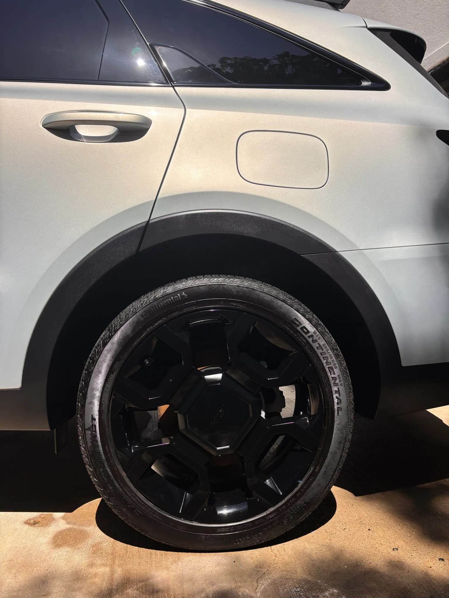 Close-up of a gloss black alloy wheel and dressed Continental tire on a white Kia Sorento.