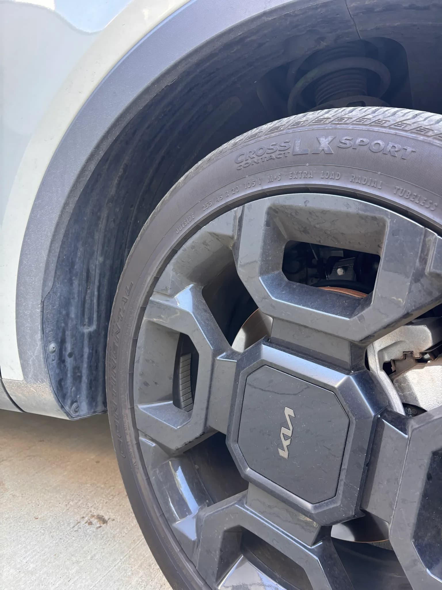Close-up of a dusty Kia alloy wheel and Continental tire before cleaning.