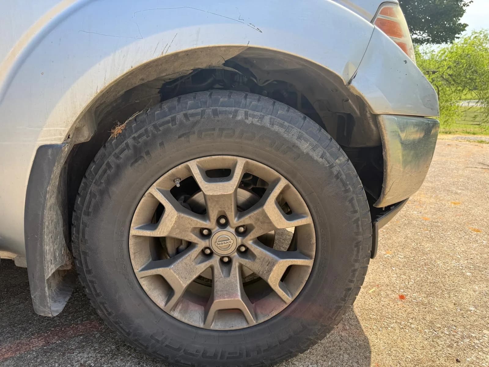 Dusty Nissan Frontier wheel and all-terrain tire before cleaning.