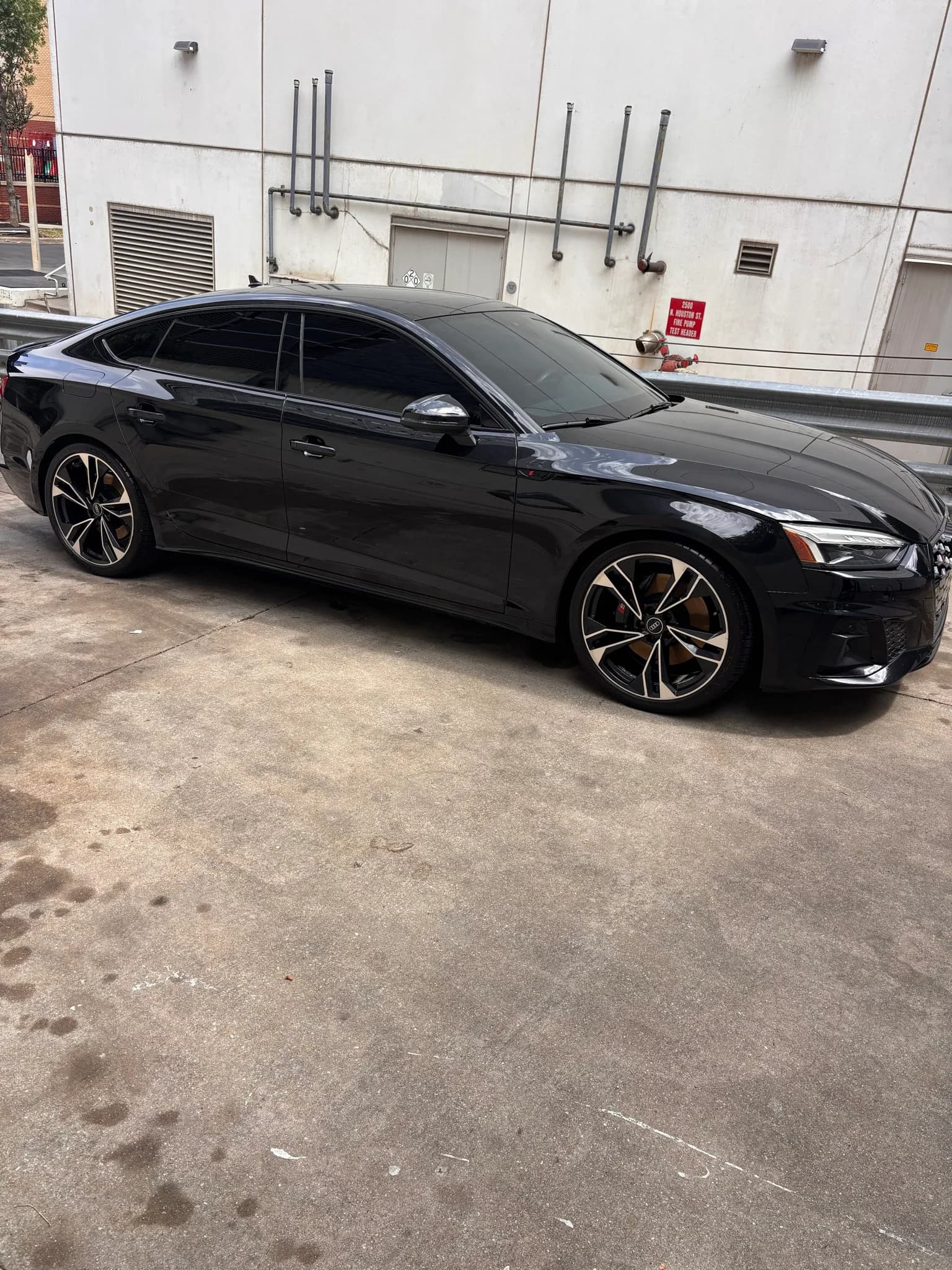 Side profile of a black Audi S5 Sportback with deeply reflective paint.