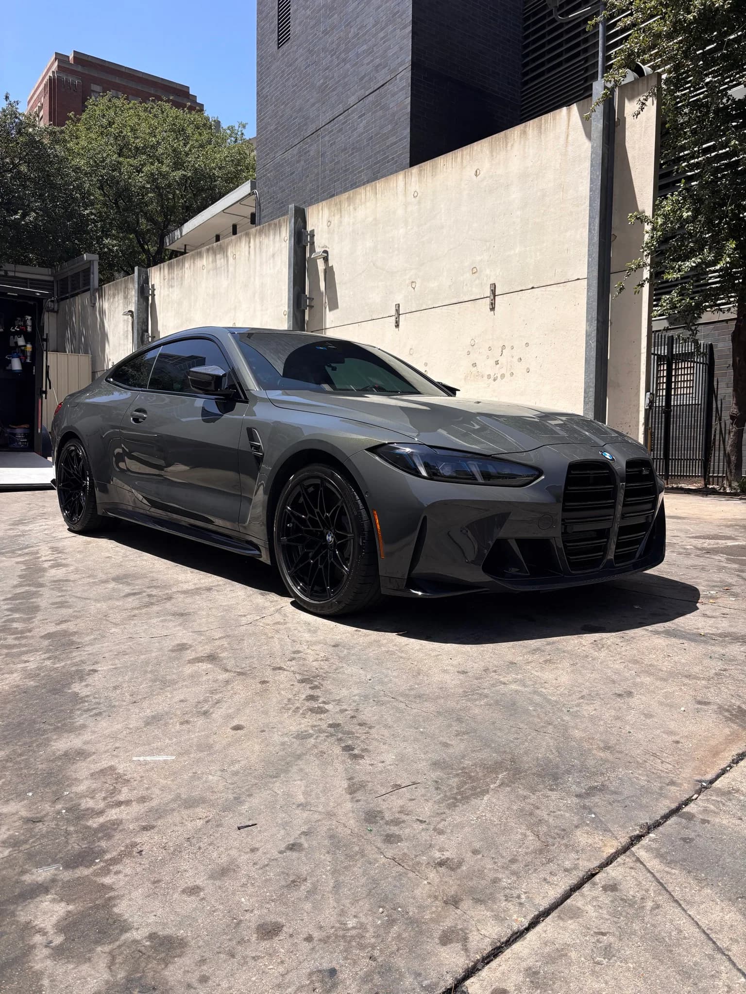 Front three-quarter view of a green BMW M4 in an alley after its detail.