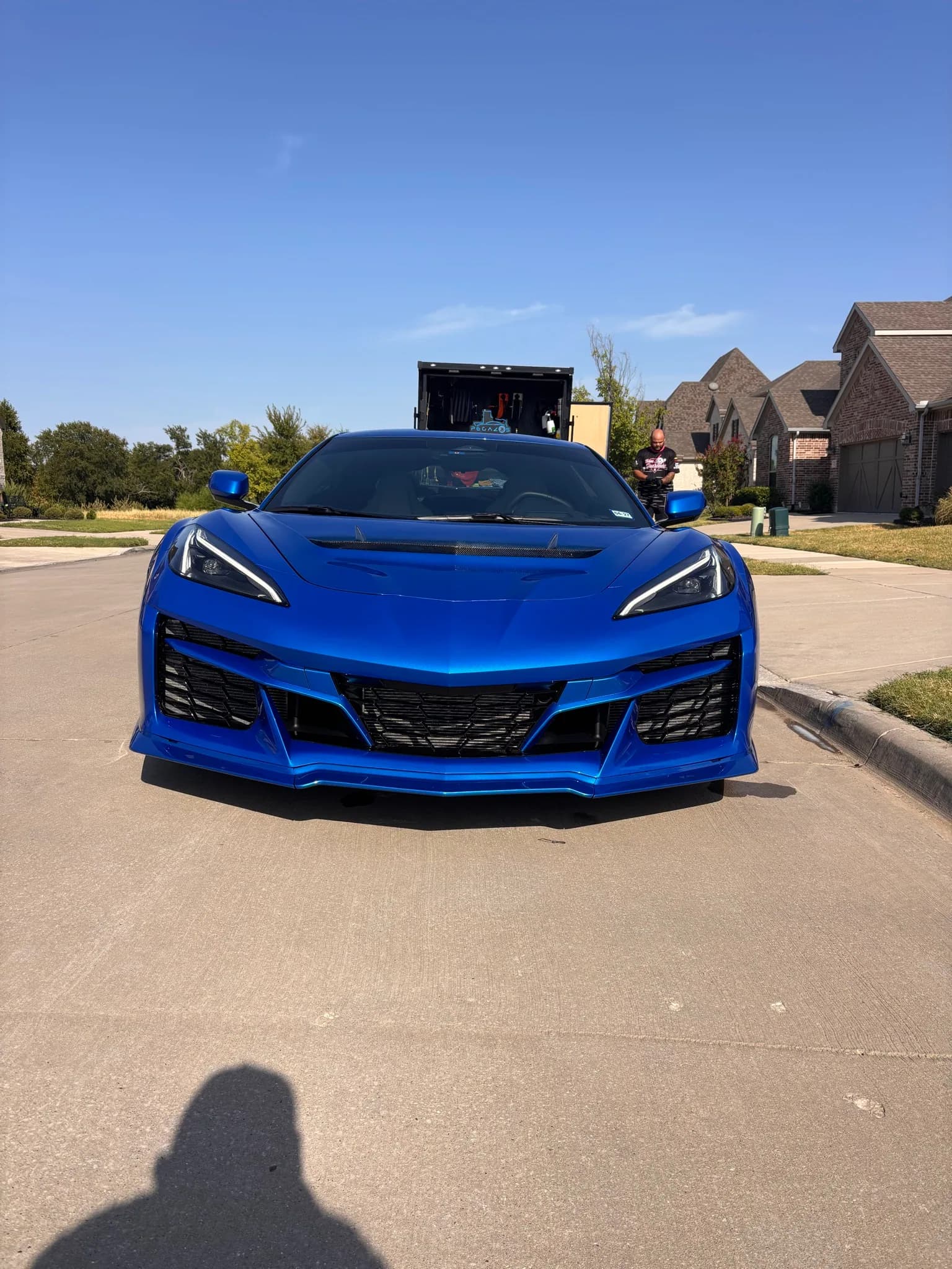 Straight-on front view of a blue Corvette C8 Z06 on a residential street.
