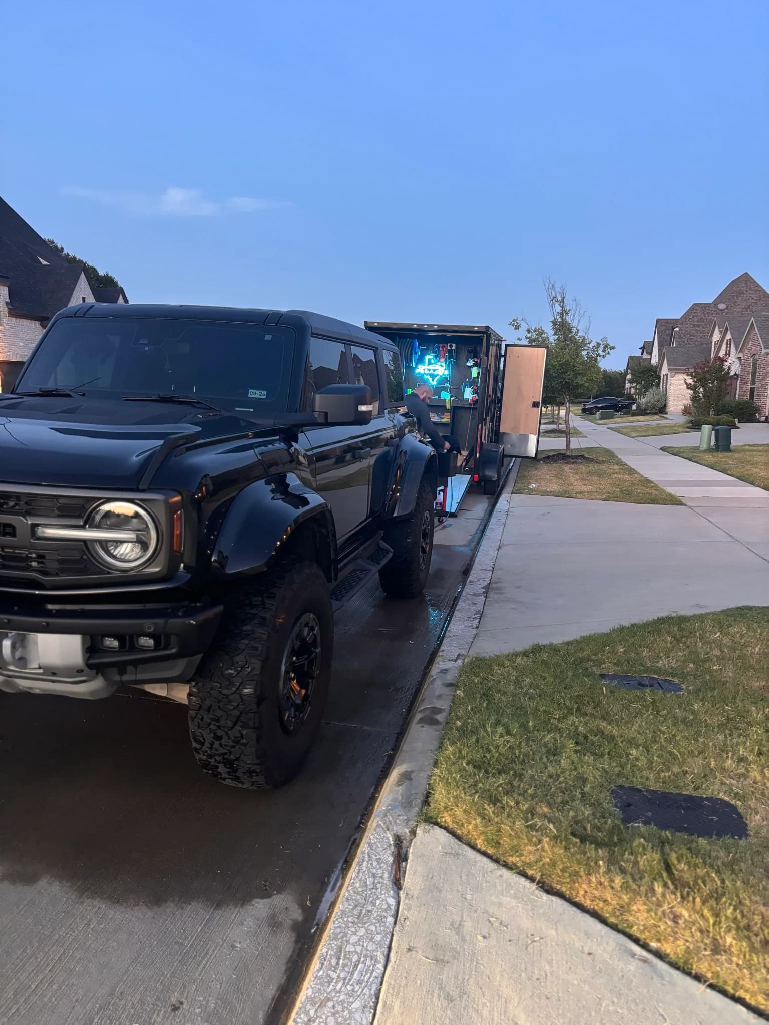 Front three-quarter view of a black Ford Bronco Raptor at dusk after its wash.