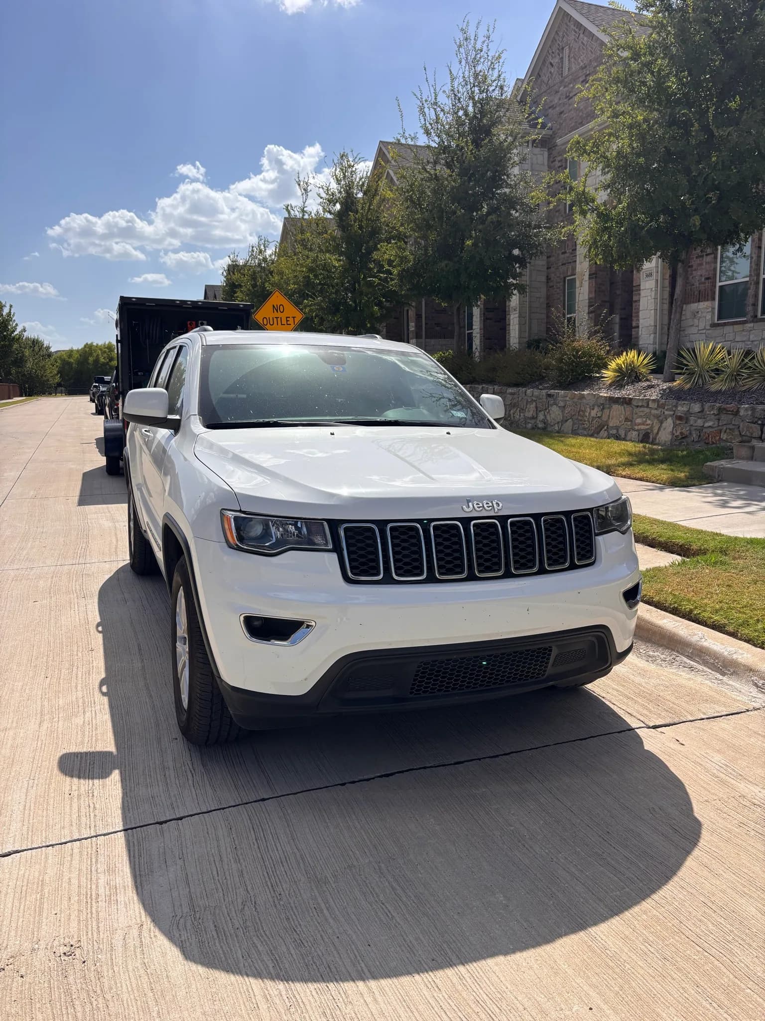 Front three-quarter view of a white Jeep Grand Cherokee on a residential street.