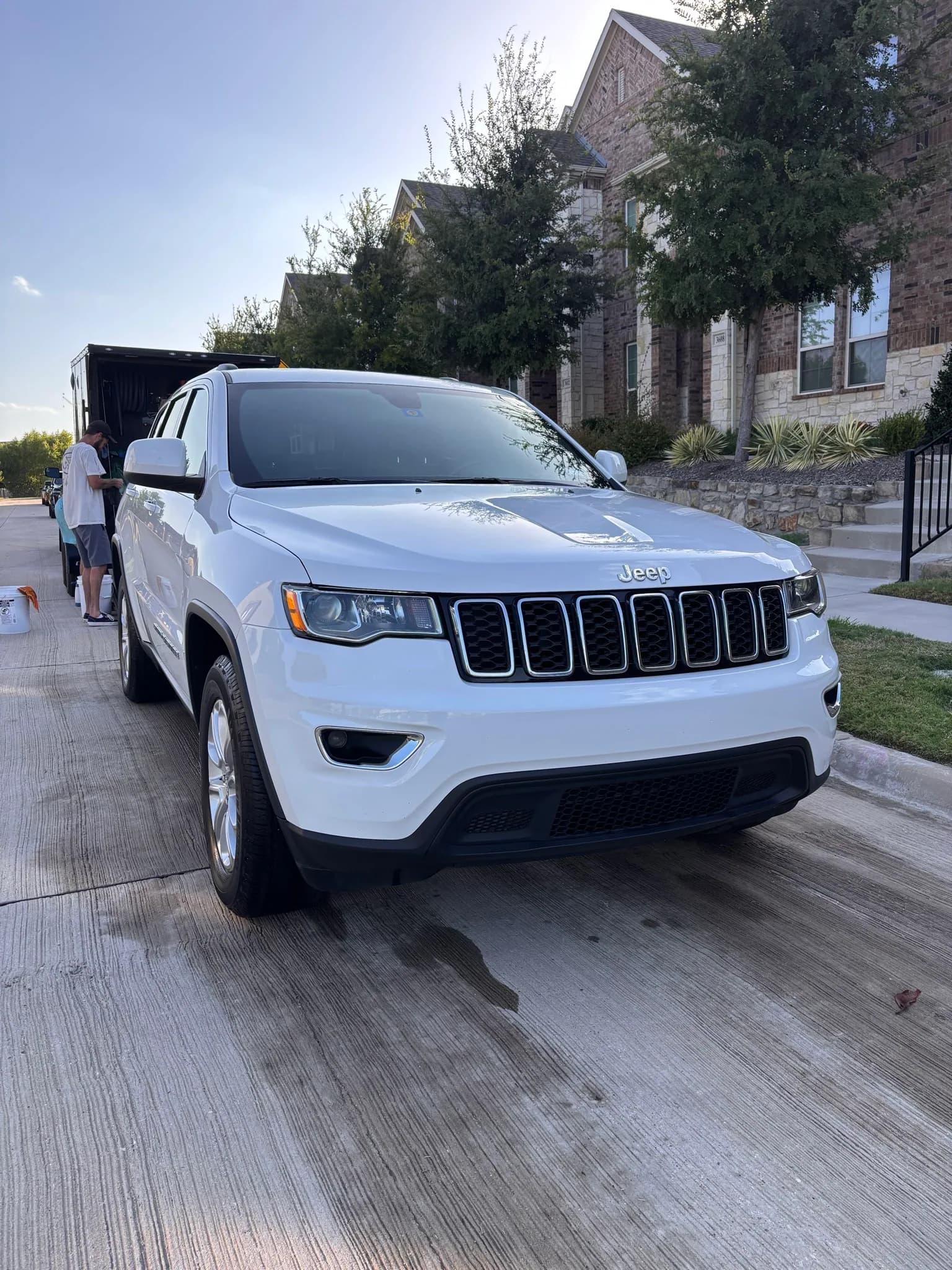 White Jeep Grand Cherokee photographed front three-quarter with the mobile rig behind.