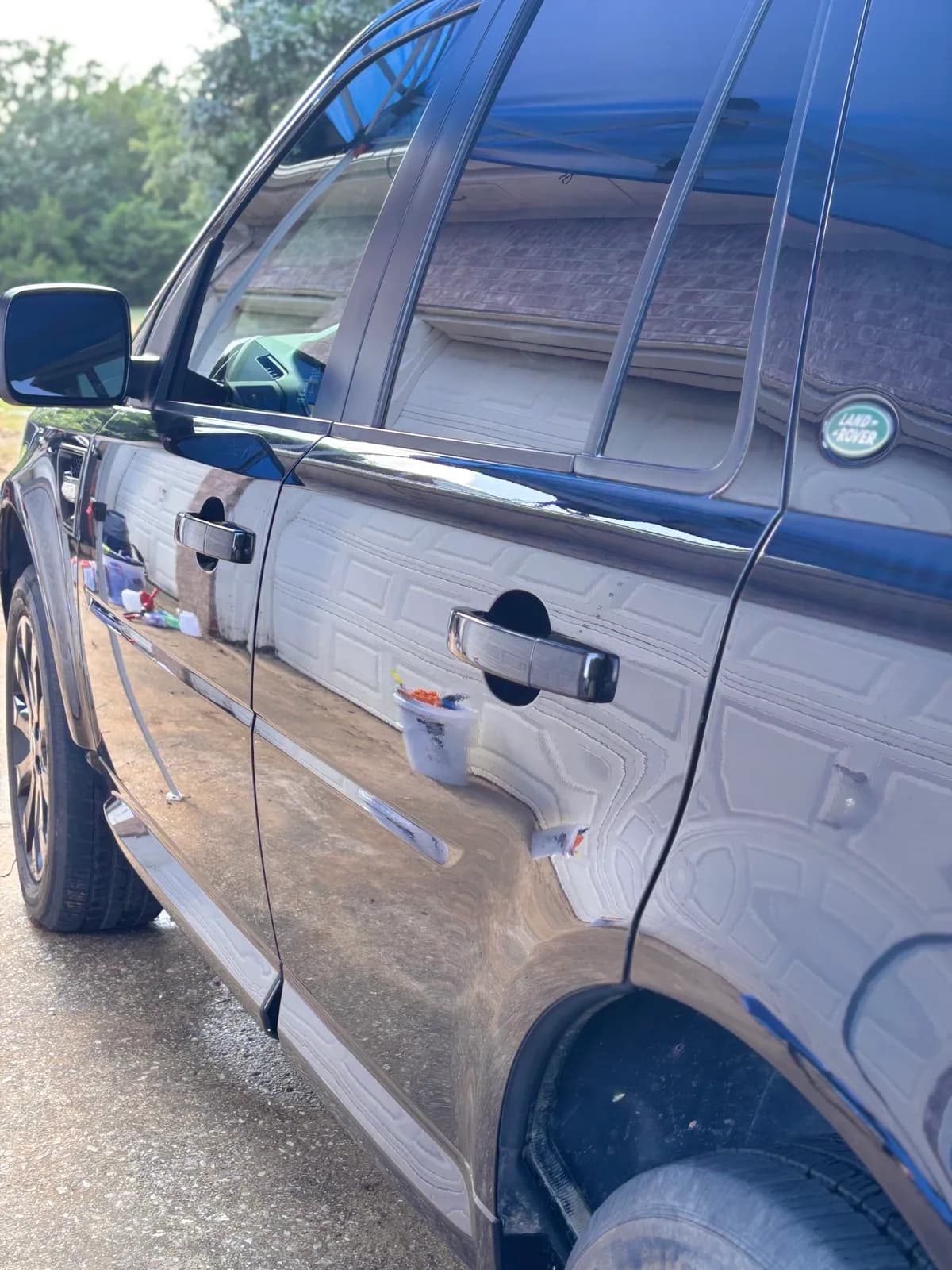 Glossy black Land Rover side doors reflecting a garage after a wash.