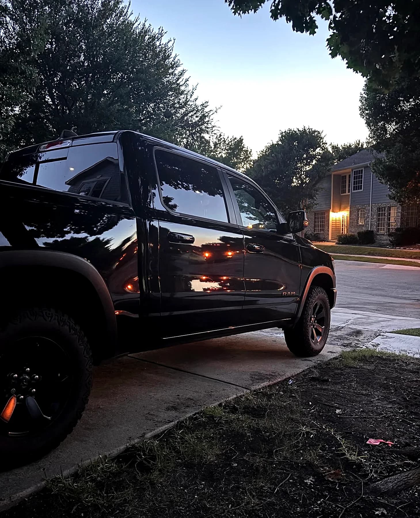 A freshly detailed black Ram 1500 Rebel on a DFW driveway at dusk, paint reflecting the sky.