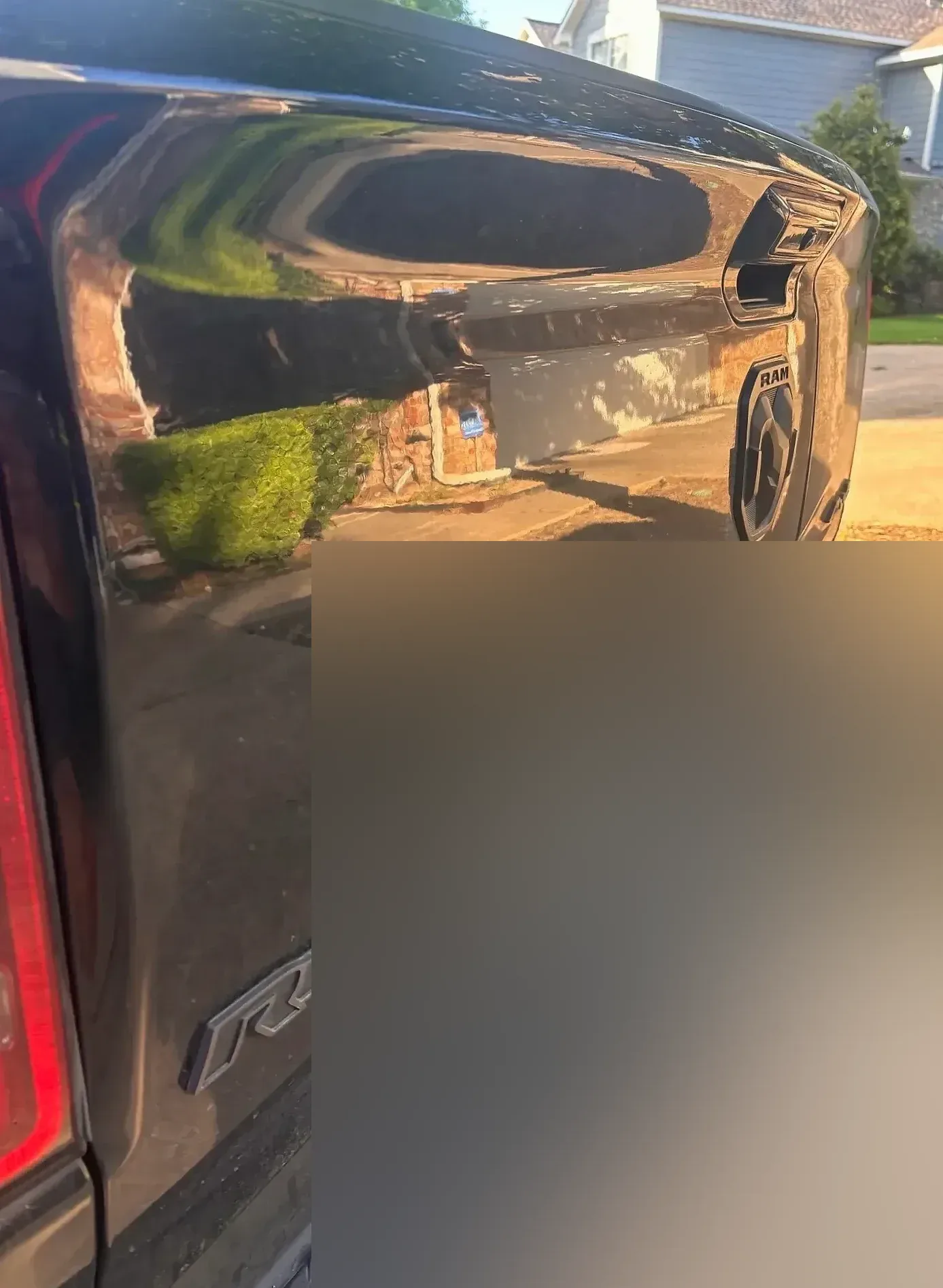 Rear tailgate of a black Ram Rebel with a mirror-like reflection.