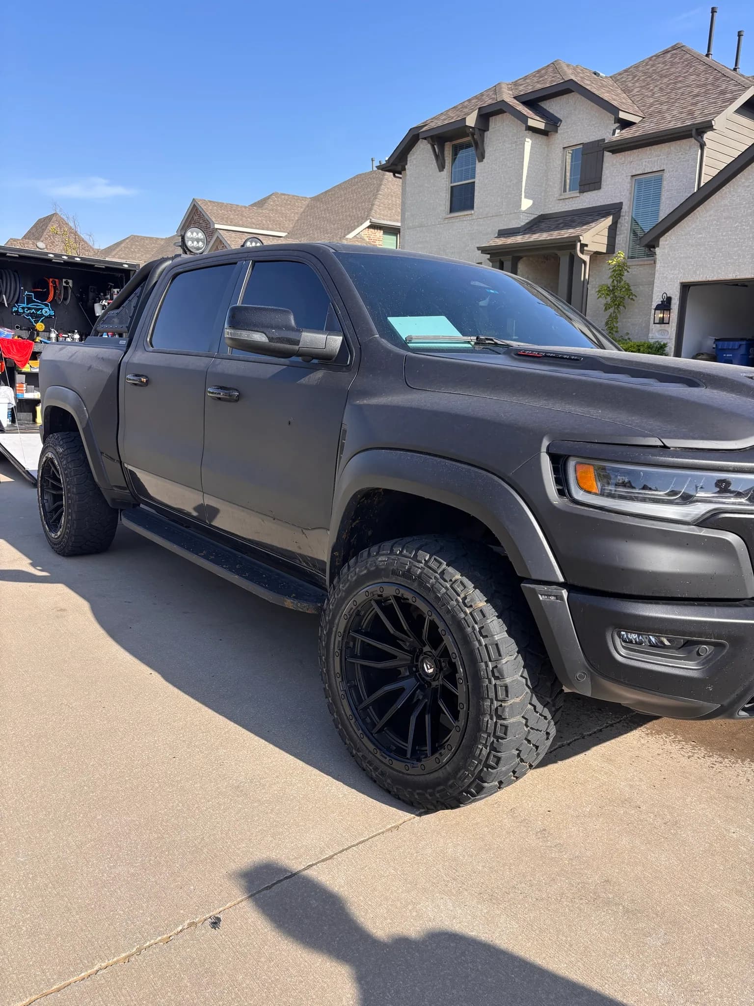 Front three-quarter view of a matte grey Ram 1500 TRX in a driveway.