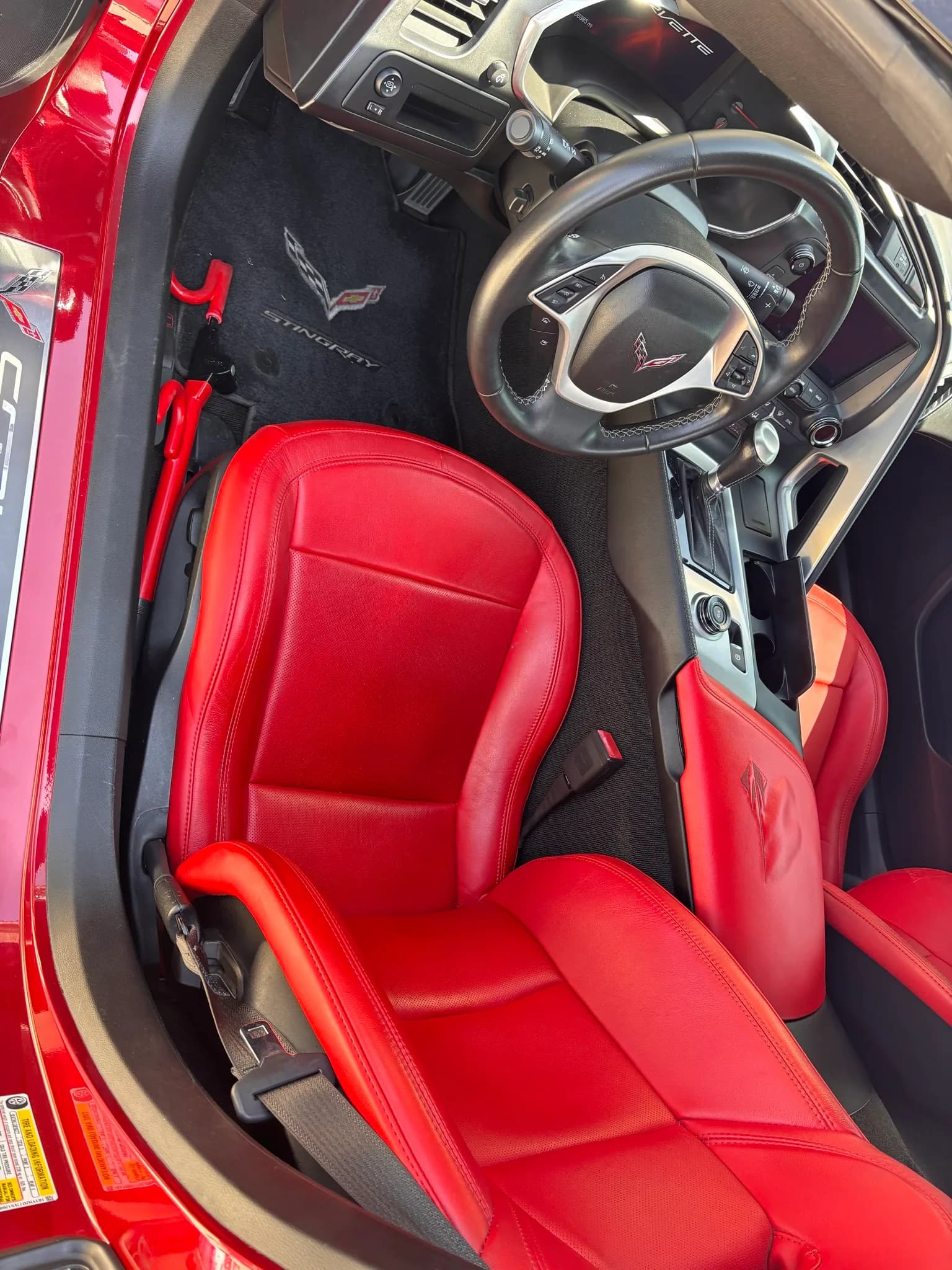 Red leather driver seat and steering wheel inside a Chevrolet Corvette after an interior detail.