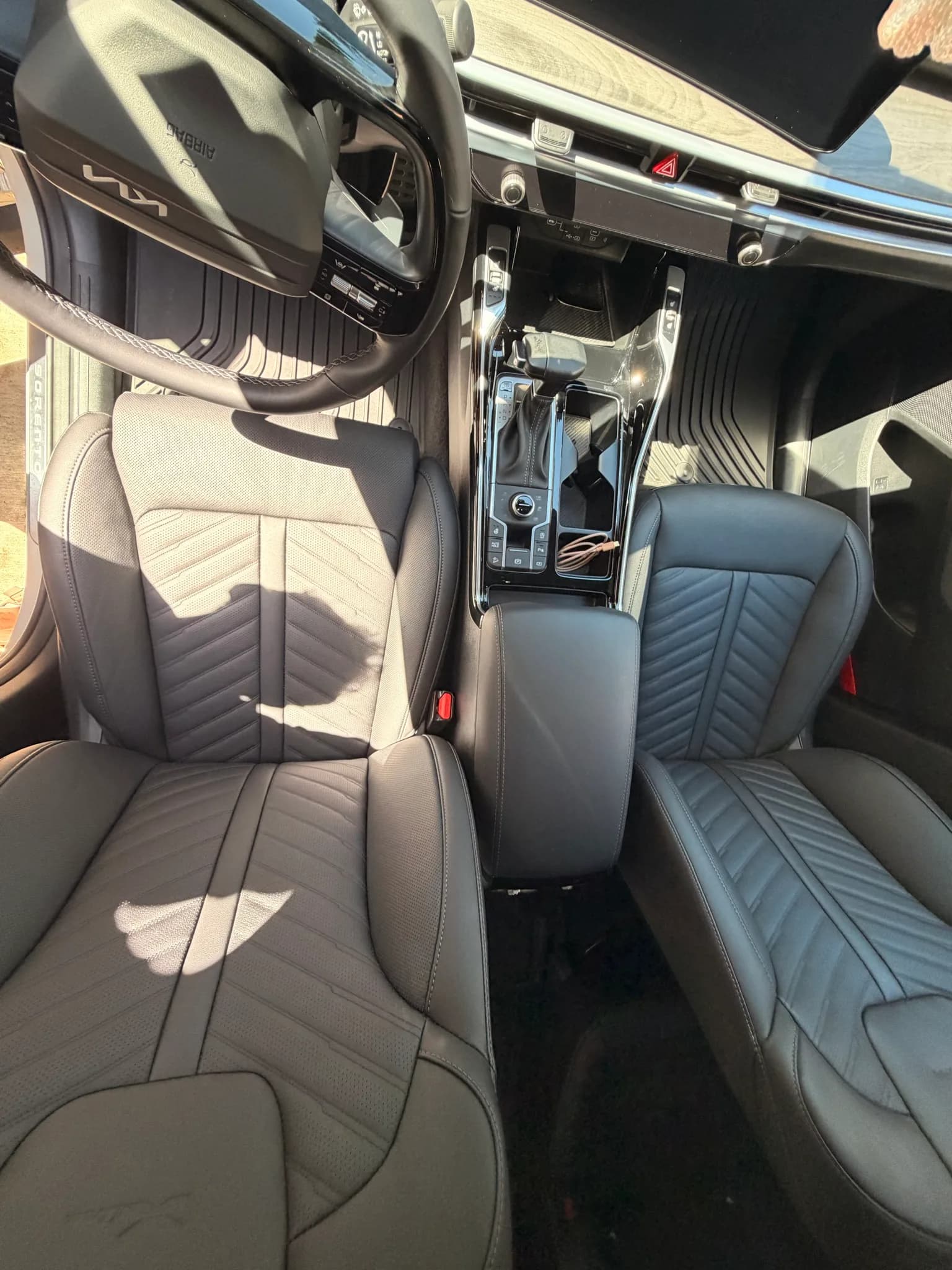 Detailed front leather seats and center console of a Kia Sorento in sunlight.