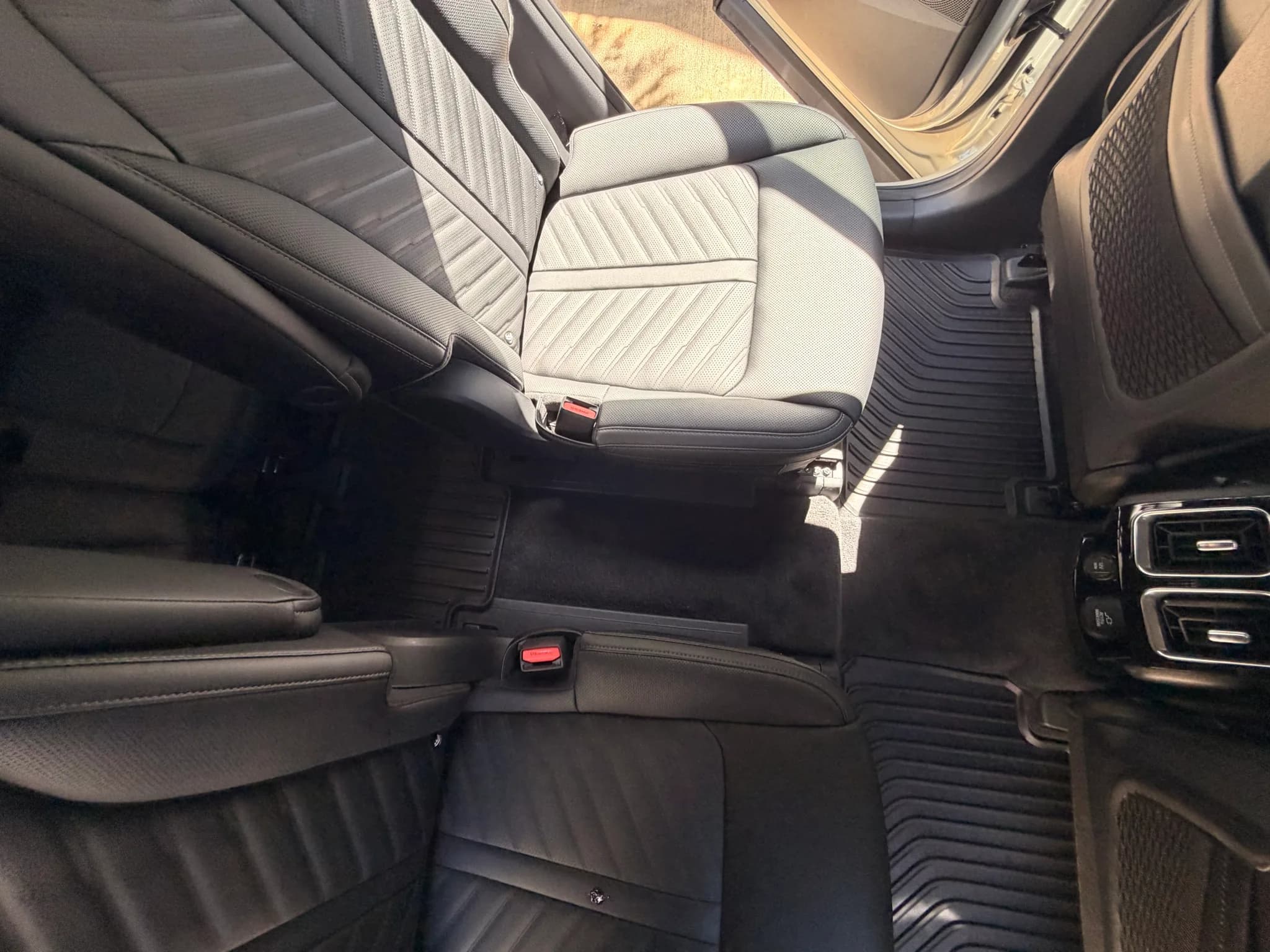 Overhead view of the cleaned second-row bench, seat belts and floor liners in a Kia Sorento.