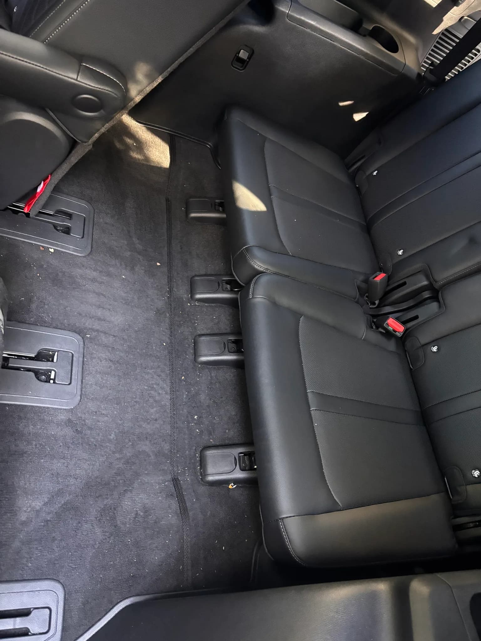 Rear cabin of a Kia Sorento showing the third-row bench and carpeted floor before cleaning.