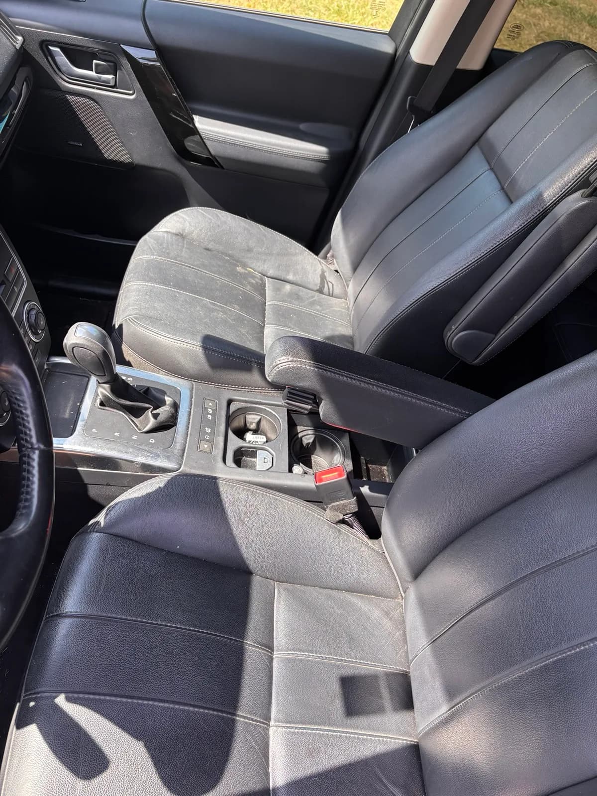 Front seats and centre console of a Land Rover LR2 with visible soiling on the leather before detailing.
