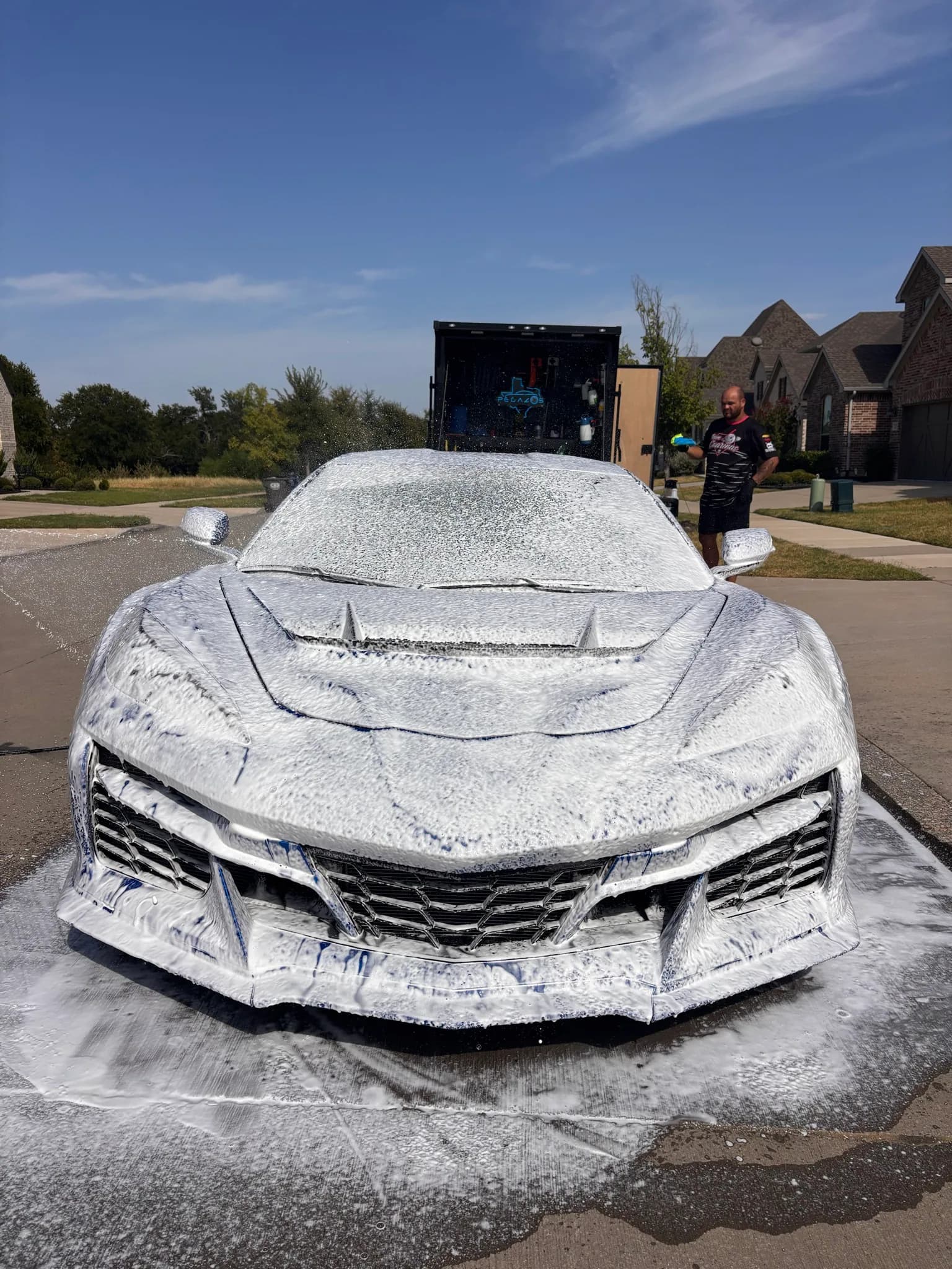 Blue Corvette C8 Z06 covered in wash foam, photographed from the front.