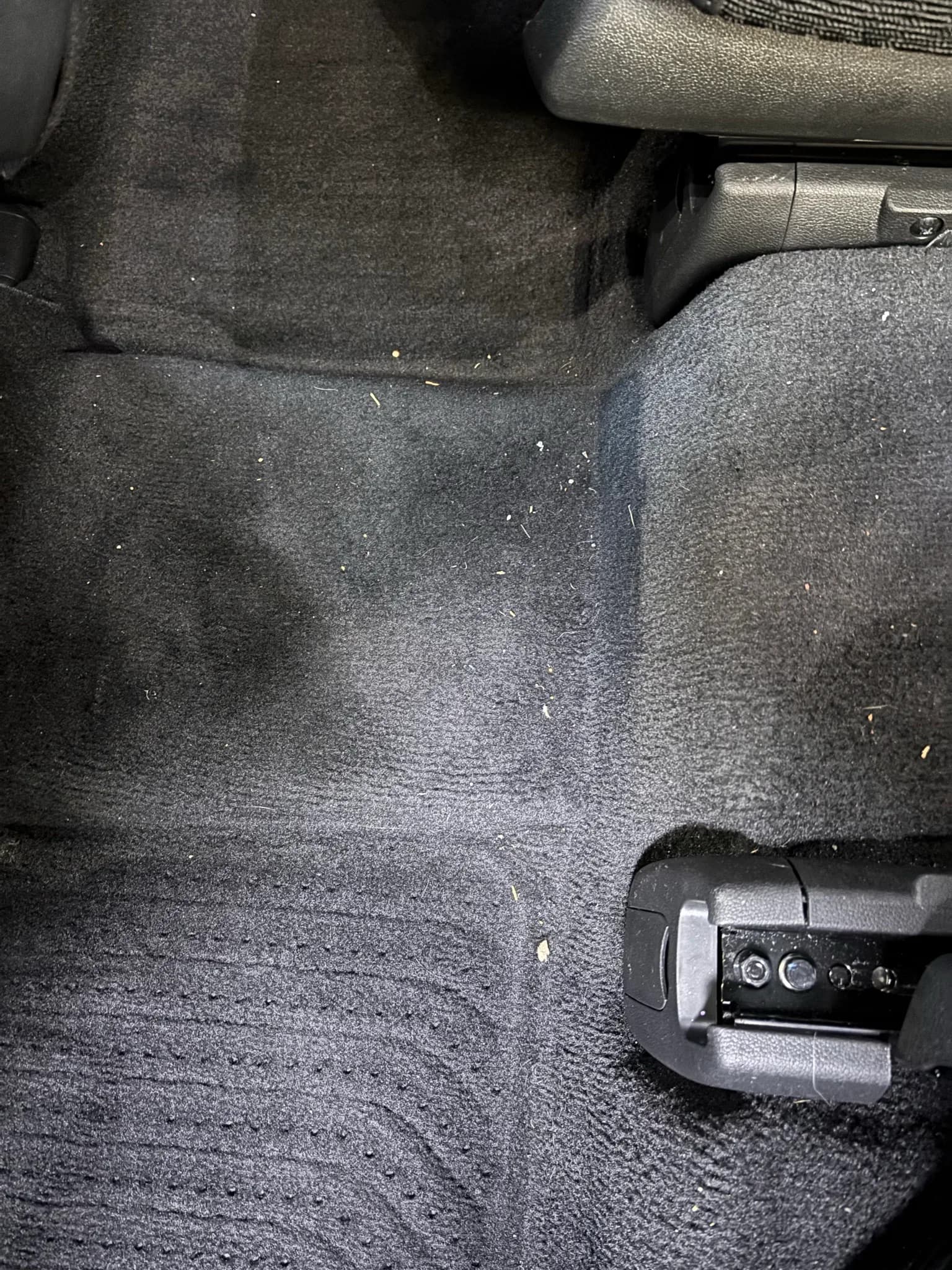 Close view of debris embedded in the rear floor carpet of a Kia Sorento.