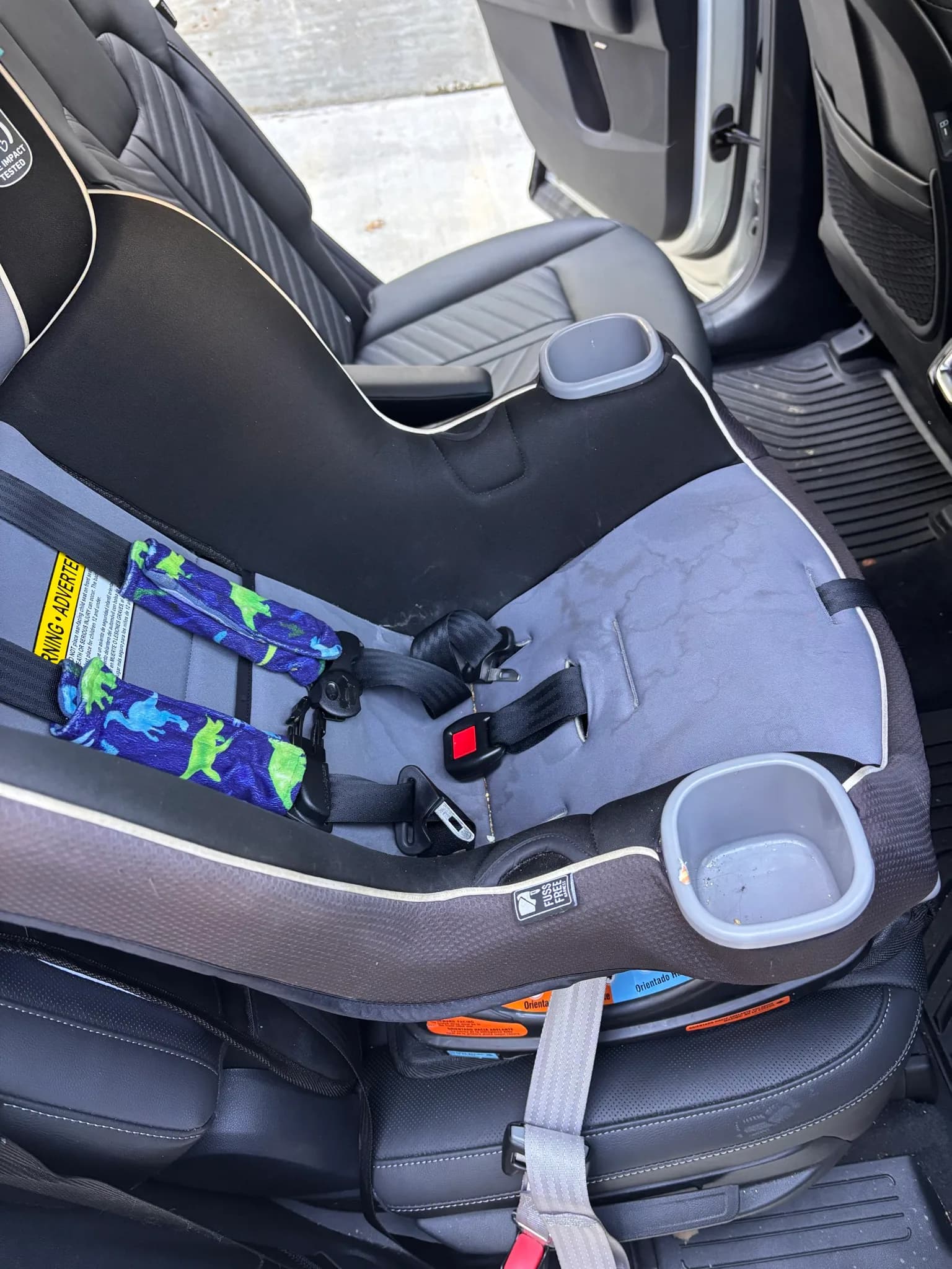 Child car seat with crumbs in the cup holder sitting in the back of a Kia Sorento before cleaning.