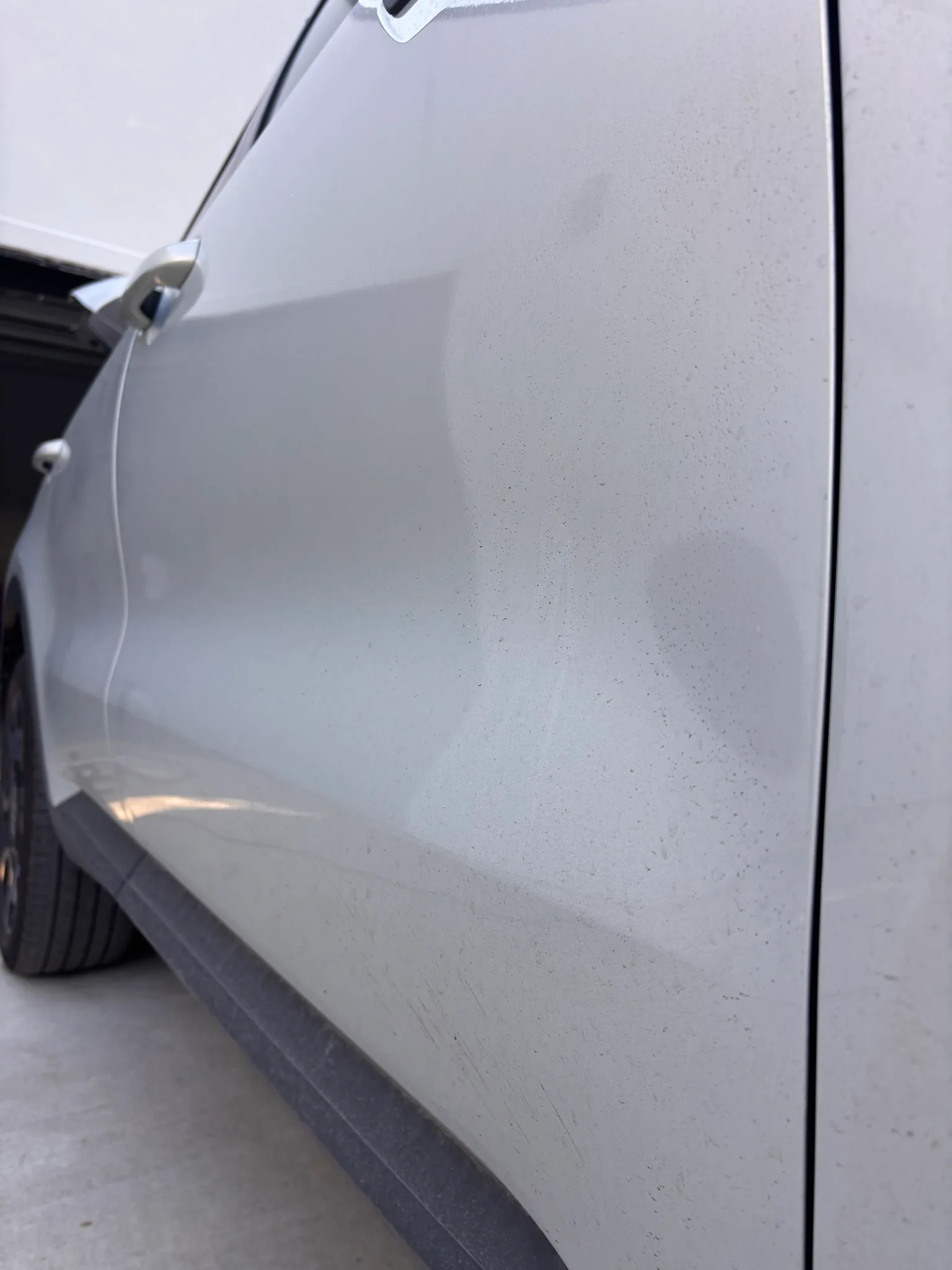 Grimy front door and side skirt of a white Kia Sorento before an exterior wash.