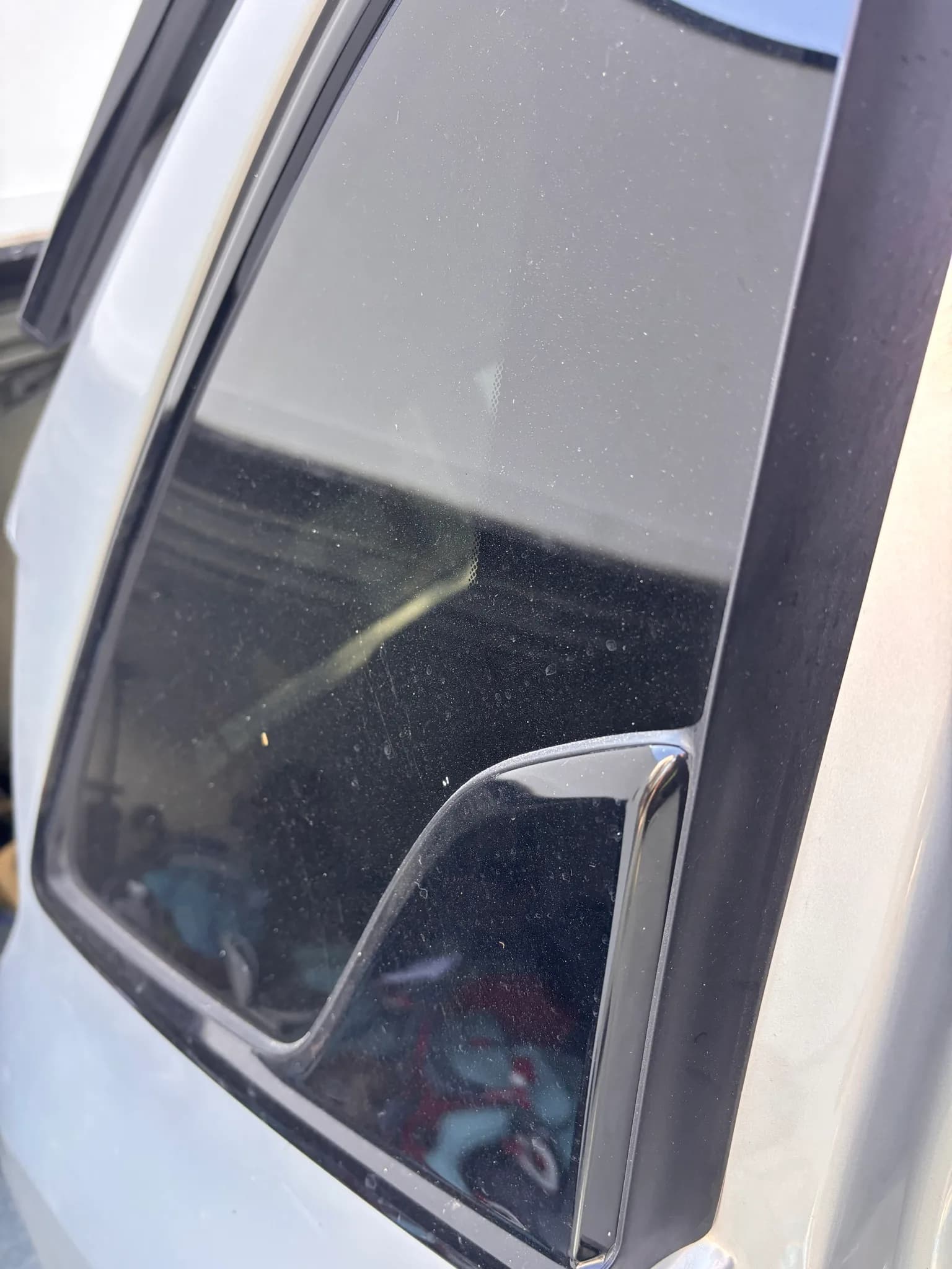Dusty rear quarter window glass on a silver Kia Sorento before washing.