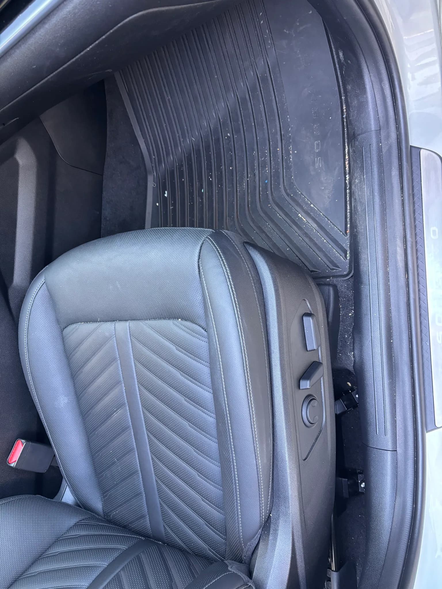 Dusty front seat, floor mat and door sill of a Kia Sorento before interior detailing.