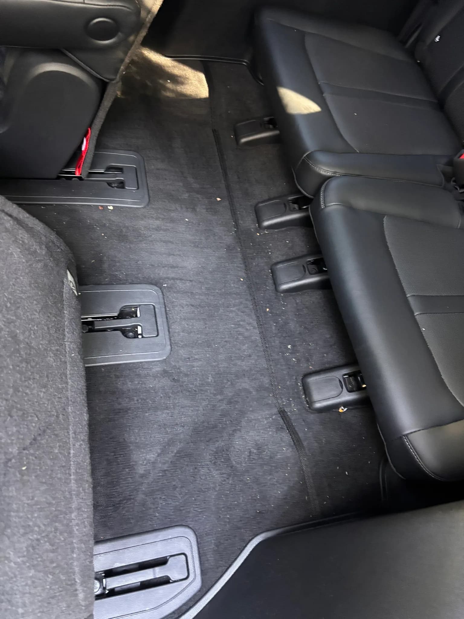 Crumbs scattered across the rear floor carpet and third-row seats of a Kia Sorento before vacuuming.