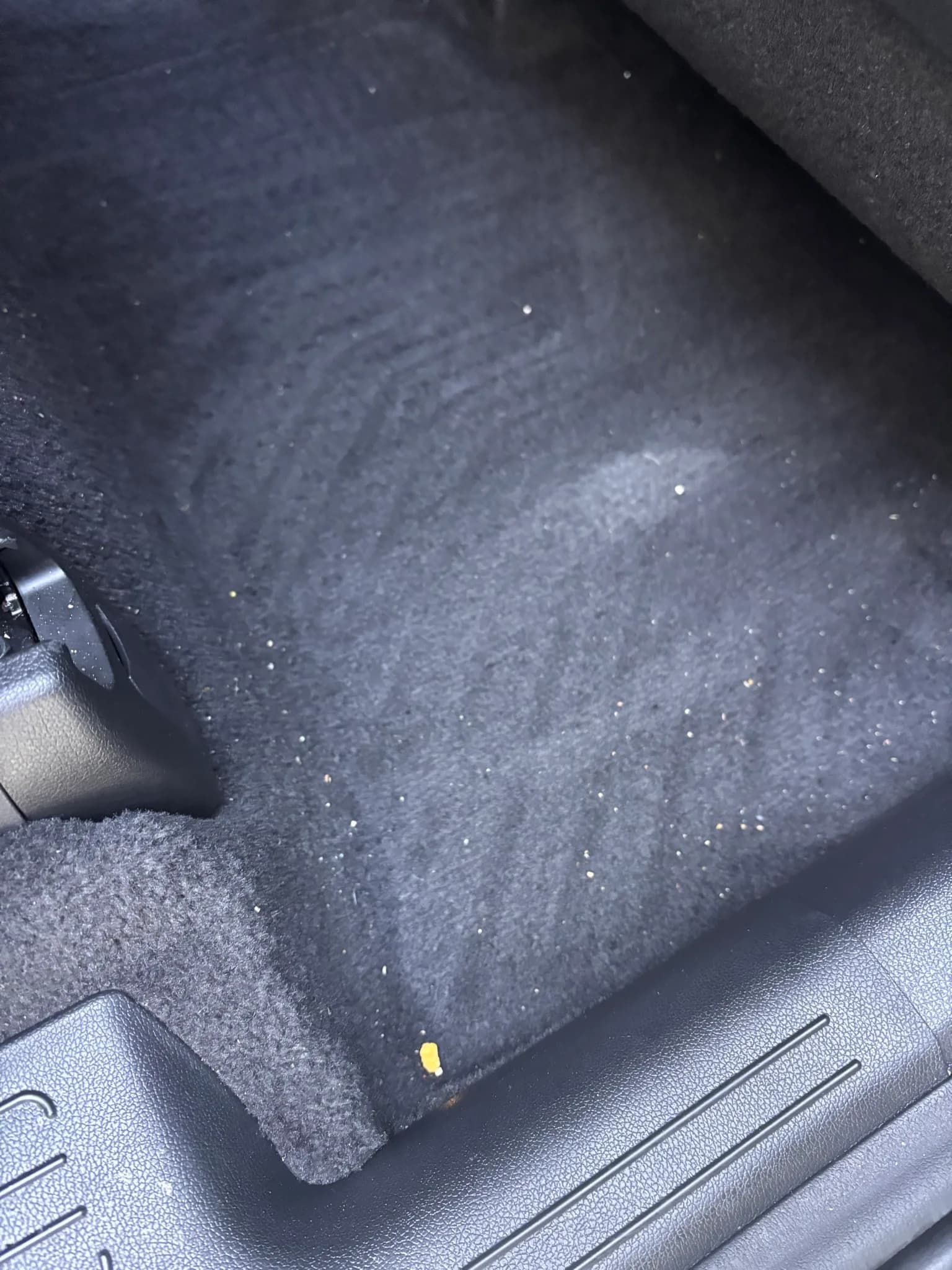 Close-up of a dusty carpet floor mat edge in a Kia Sorento before cleaning.