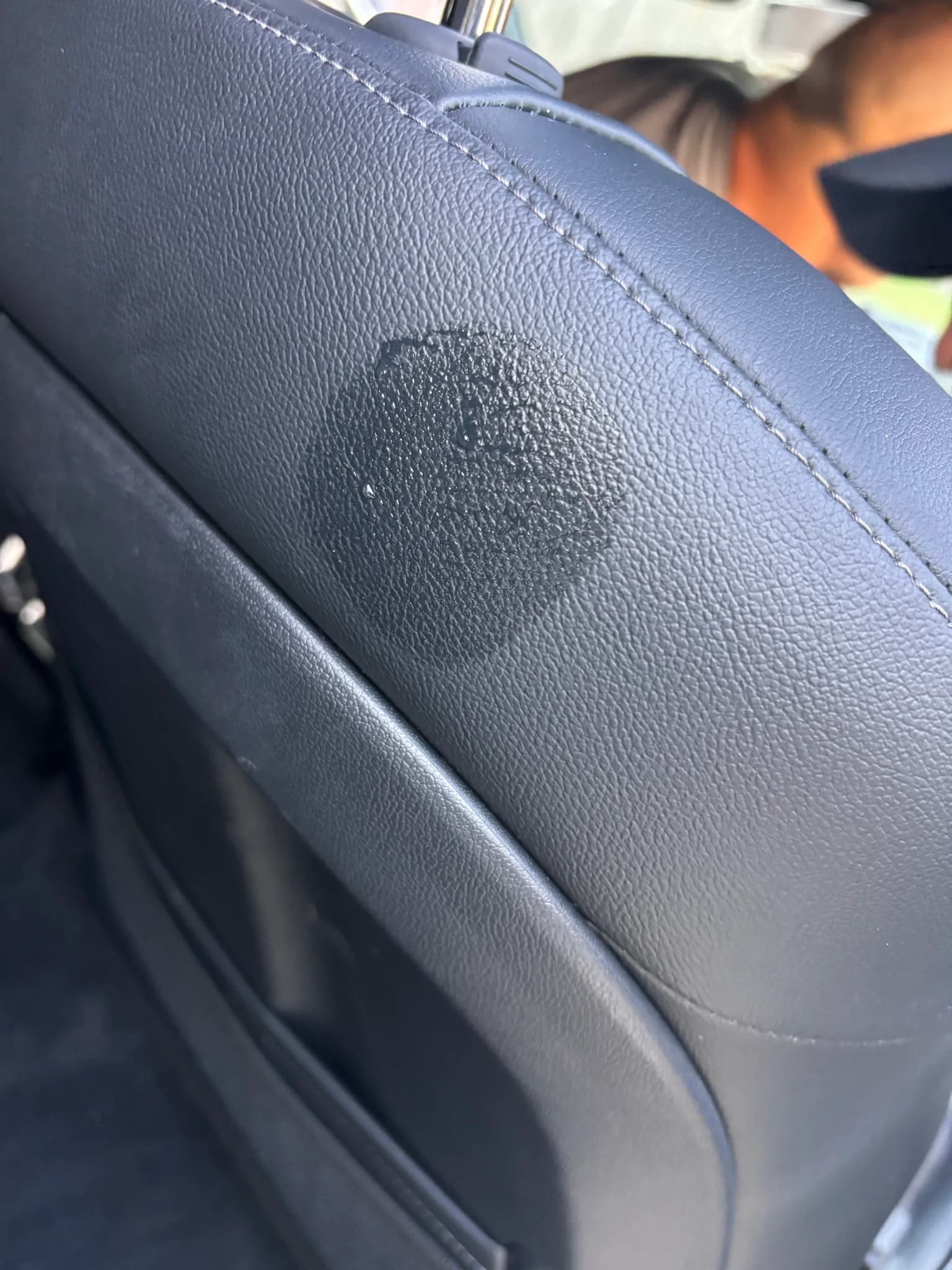 Stain on the leather seat back of a Kia Sorento before spot cleaning.