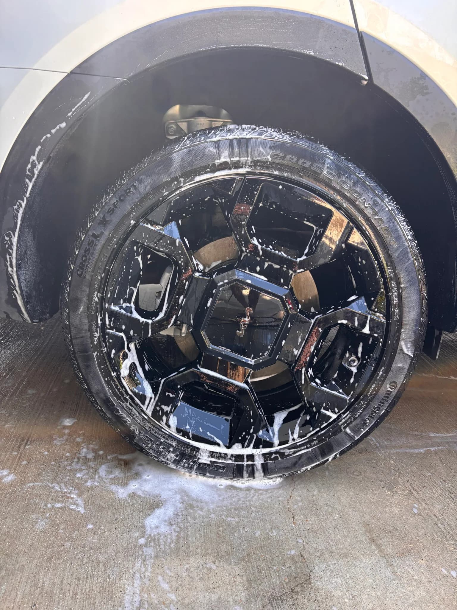 Kia Sorento wheel being agitated with soap and a detailing brush.