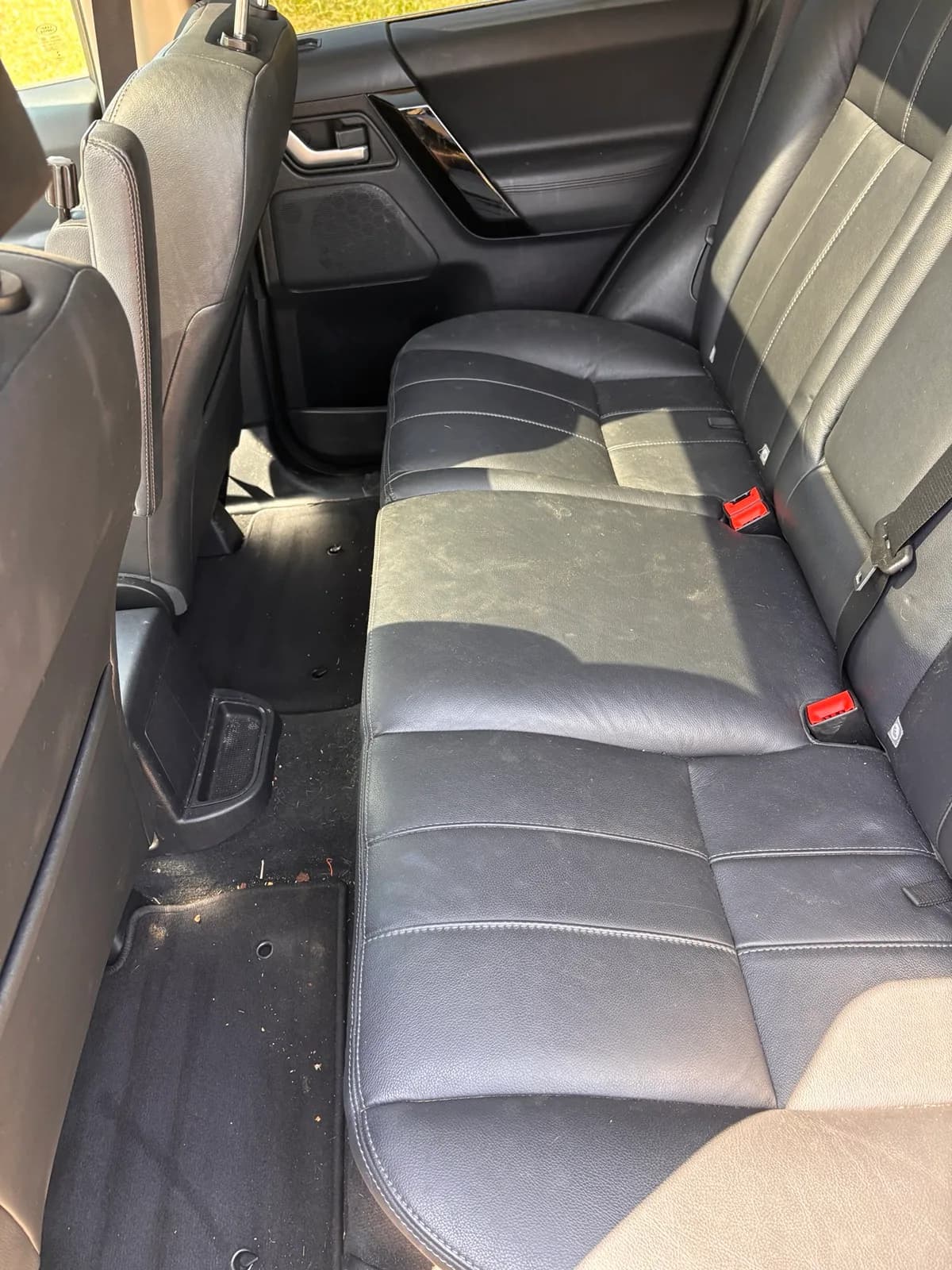 Wide view of the soiled rear leather bench and carpet in a Land Rover LR2 before cleaning.