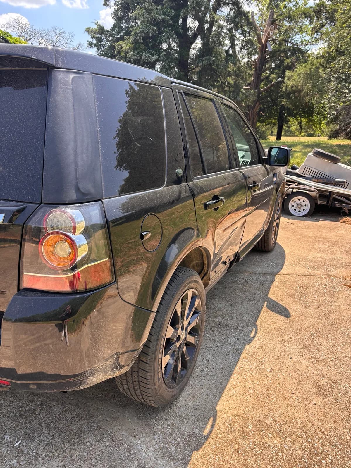 Dust-covered black Land Rover LR2 seen from the rear side before its mobile detail.