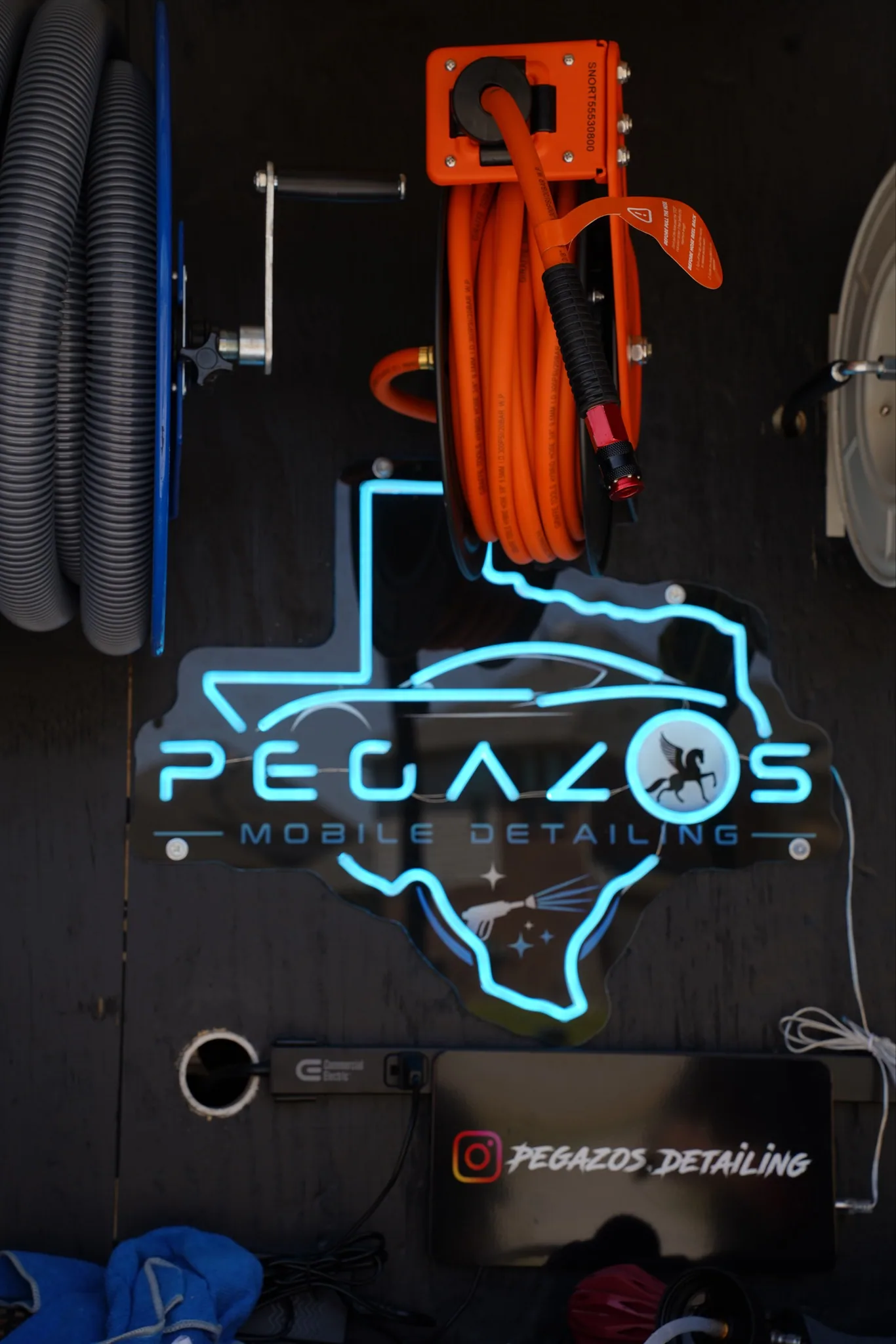 Neon Pegazos Mobile Detailing sign beside the coiled pressure hose reel.