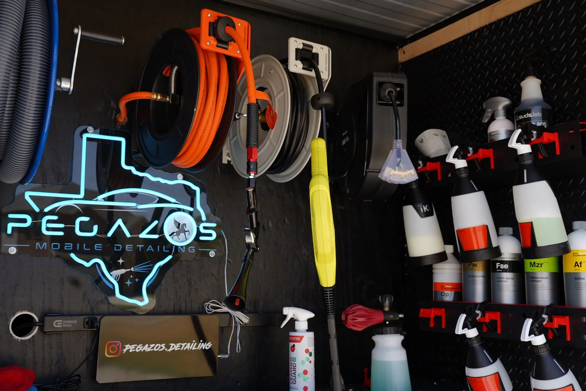 Interior trailer wall with the hose reel, chemical shelf and neon sign.