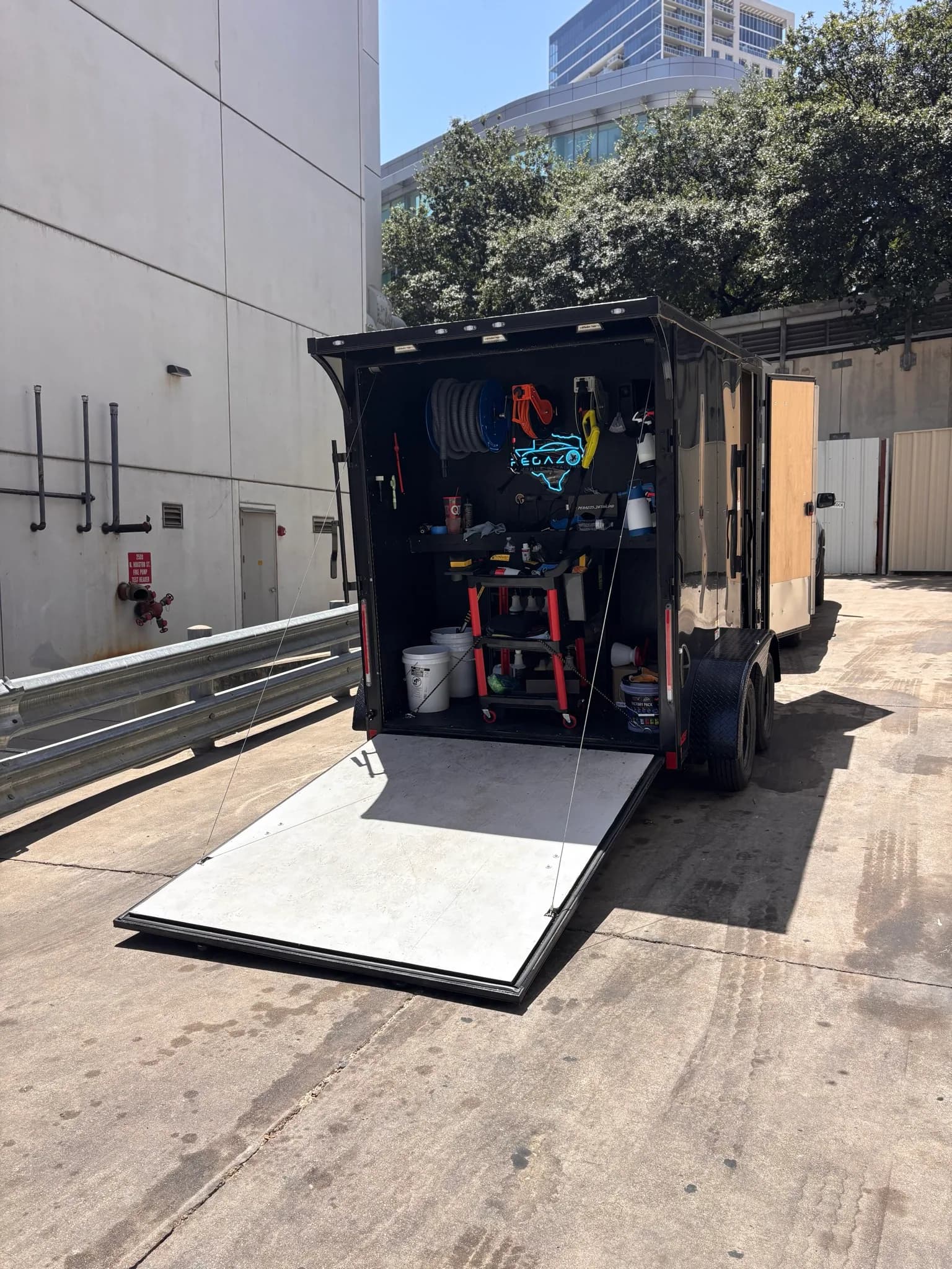 The Pegazos Detailing trailer open with its ramp down and equipment racked inside.
