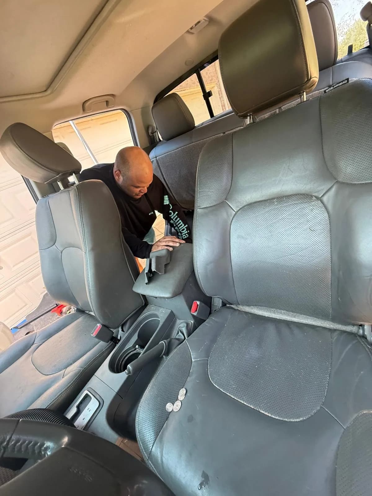 Detailer removing the rear seat cushion from a Nissan Frontier for deeper access.