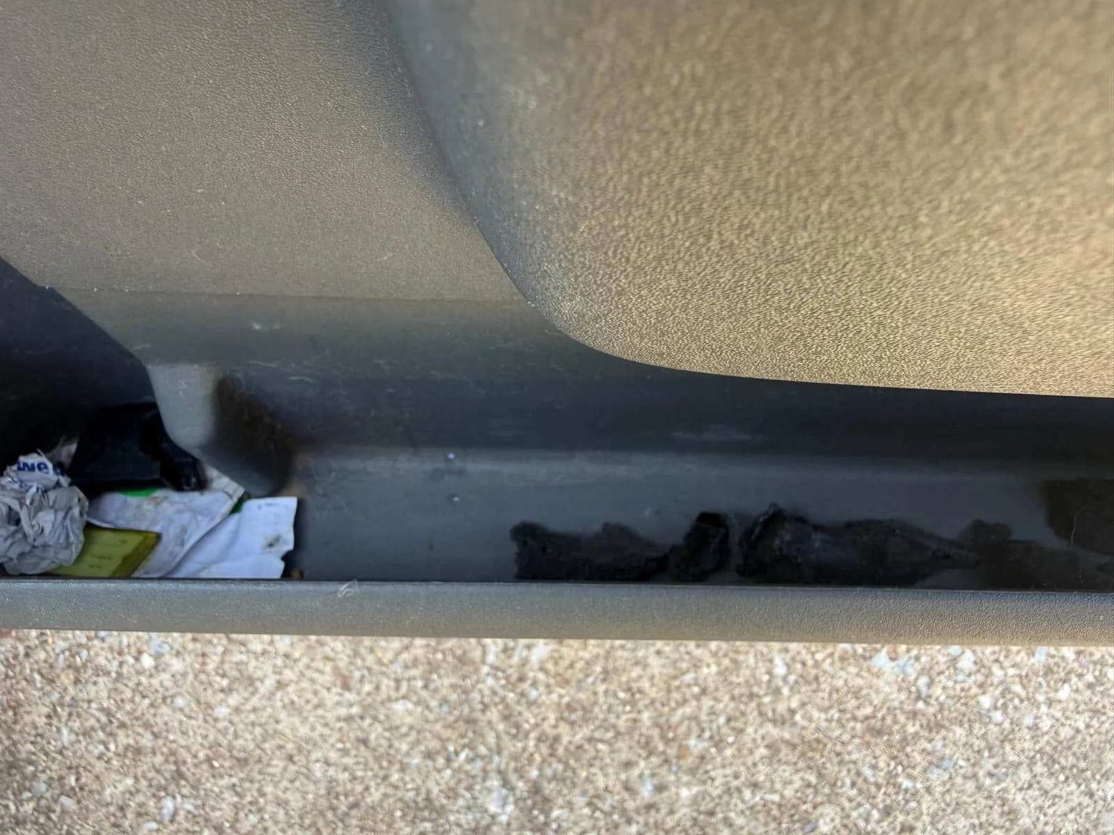 Debris and trash lodged in a truck door sill before cleaning.