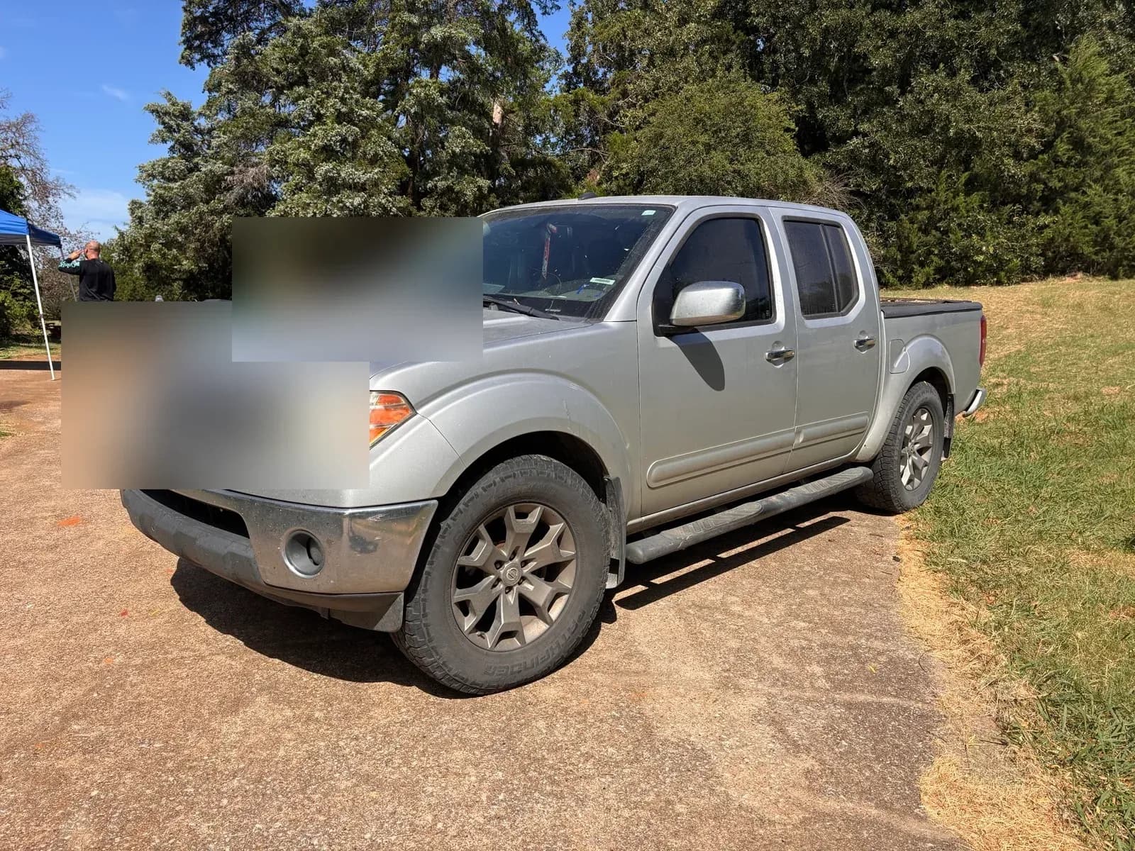 Dusty silver Nissan Frontier pickup waiting to be detailed, with a detailing canopy set up behind it.