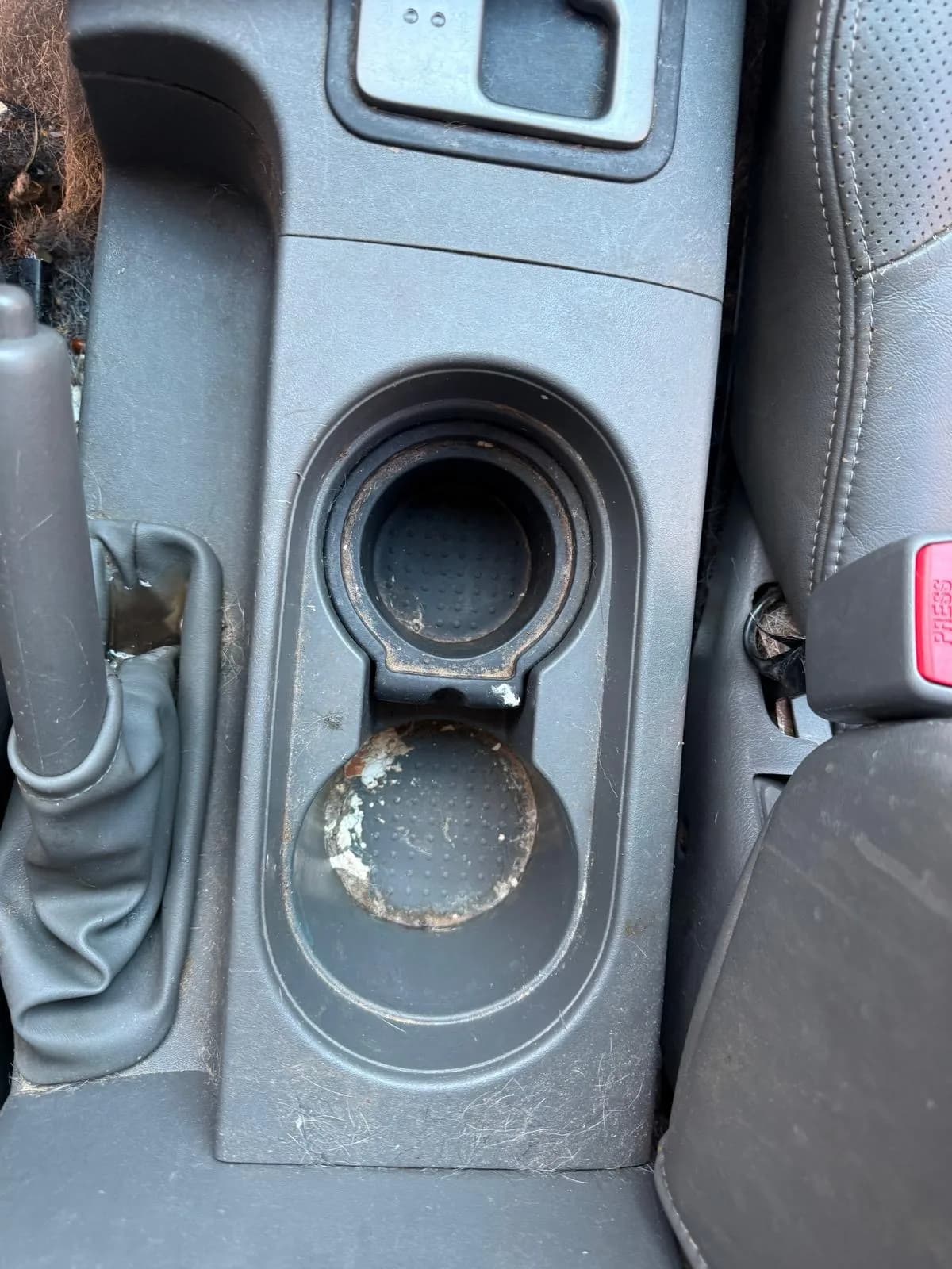 Grimy cup holders caked with dried spills before interior cleaning.