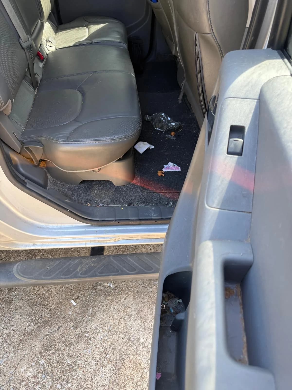 Rear seat and floor of a truck littered with trash before interior detailing.
