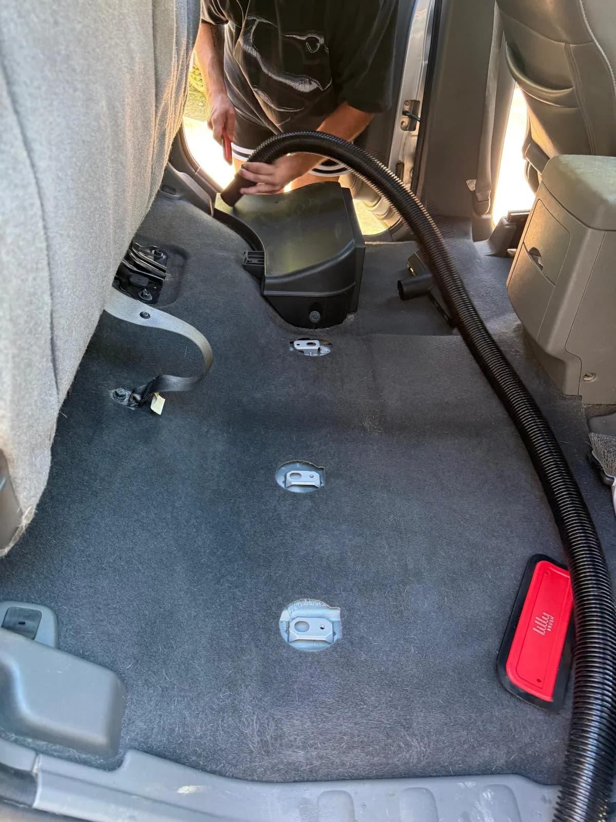Nissan Frontier rear carpet being vacuumed with the seat removed.